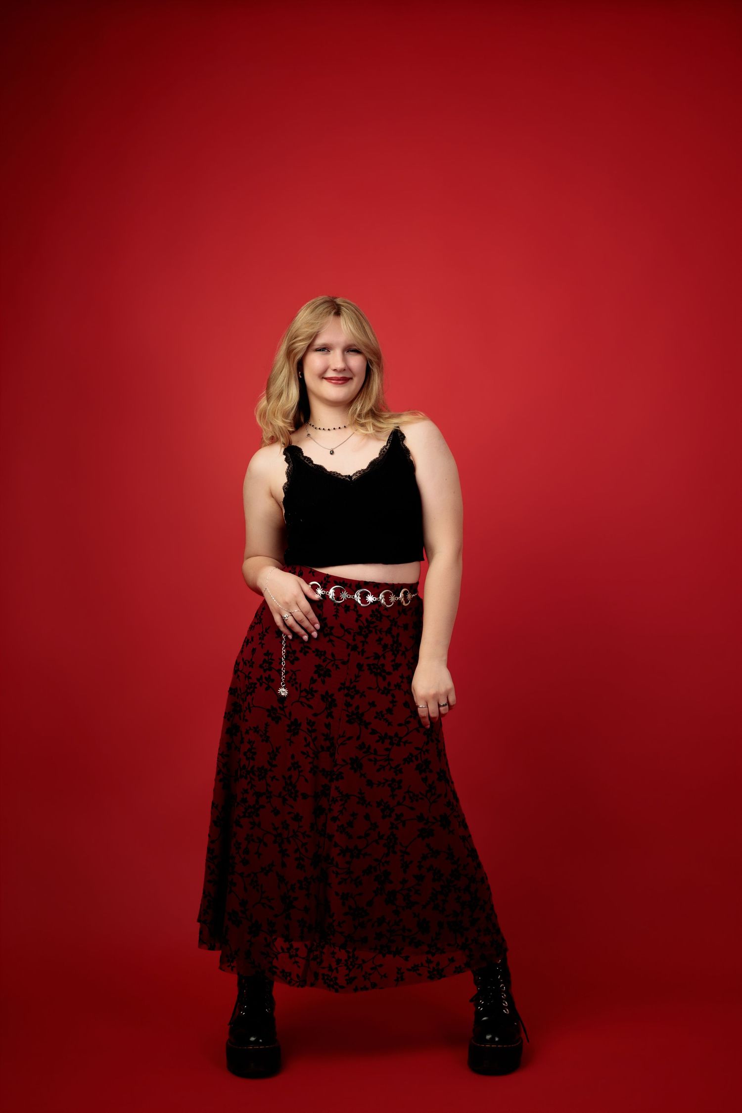 A sequence of fashion portraits against a vibrant red background featuring a black dress and expressive poses.