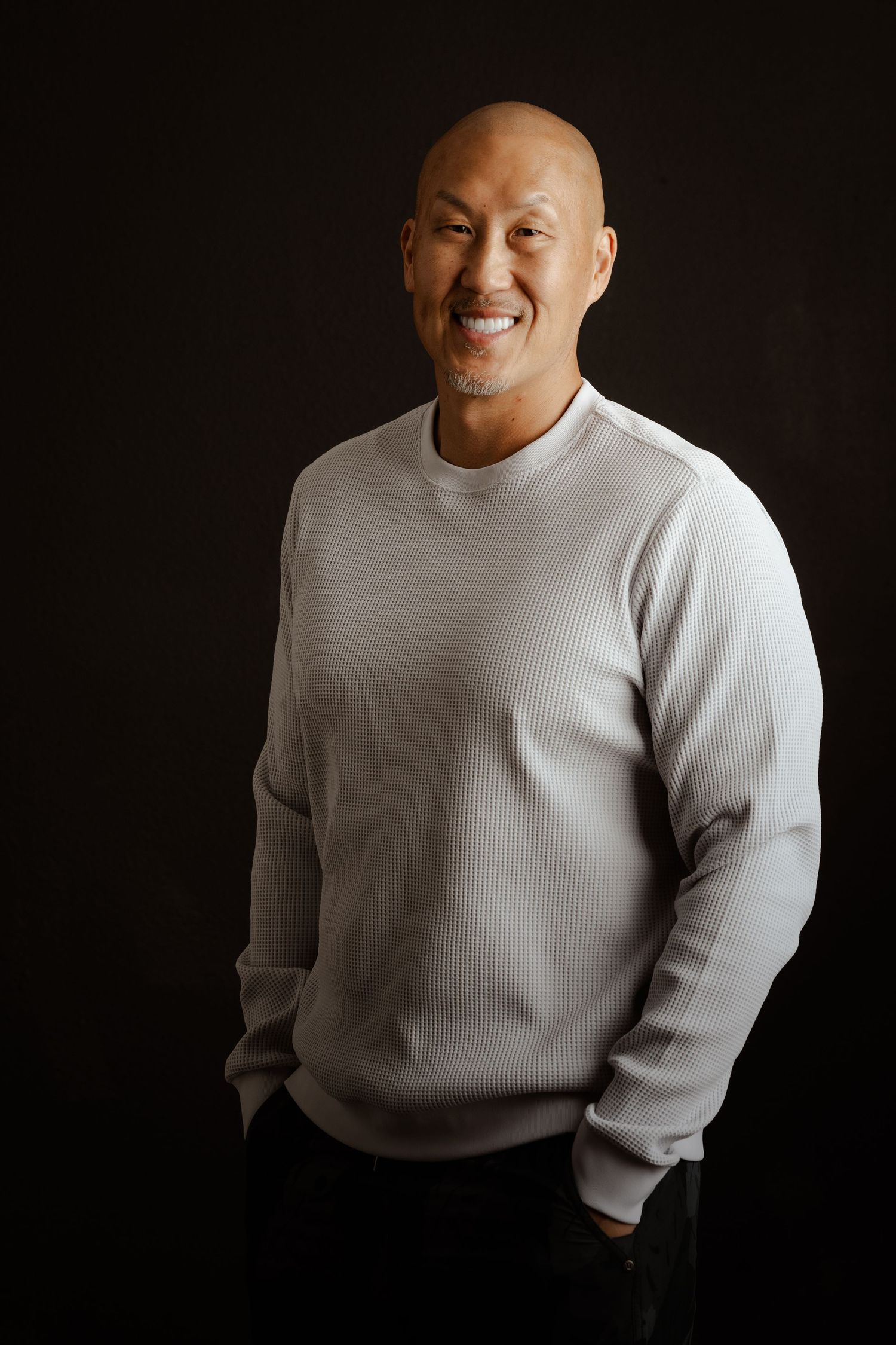 Person wearing a white ribbed sweater poses against a dark background in a series of candid expressions.