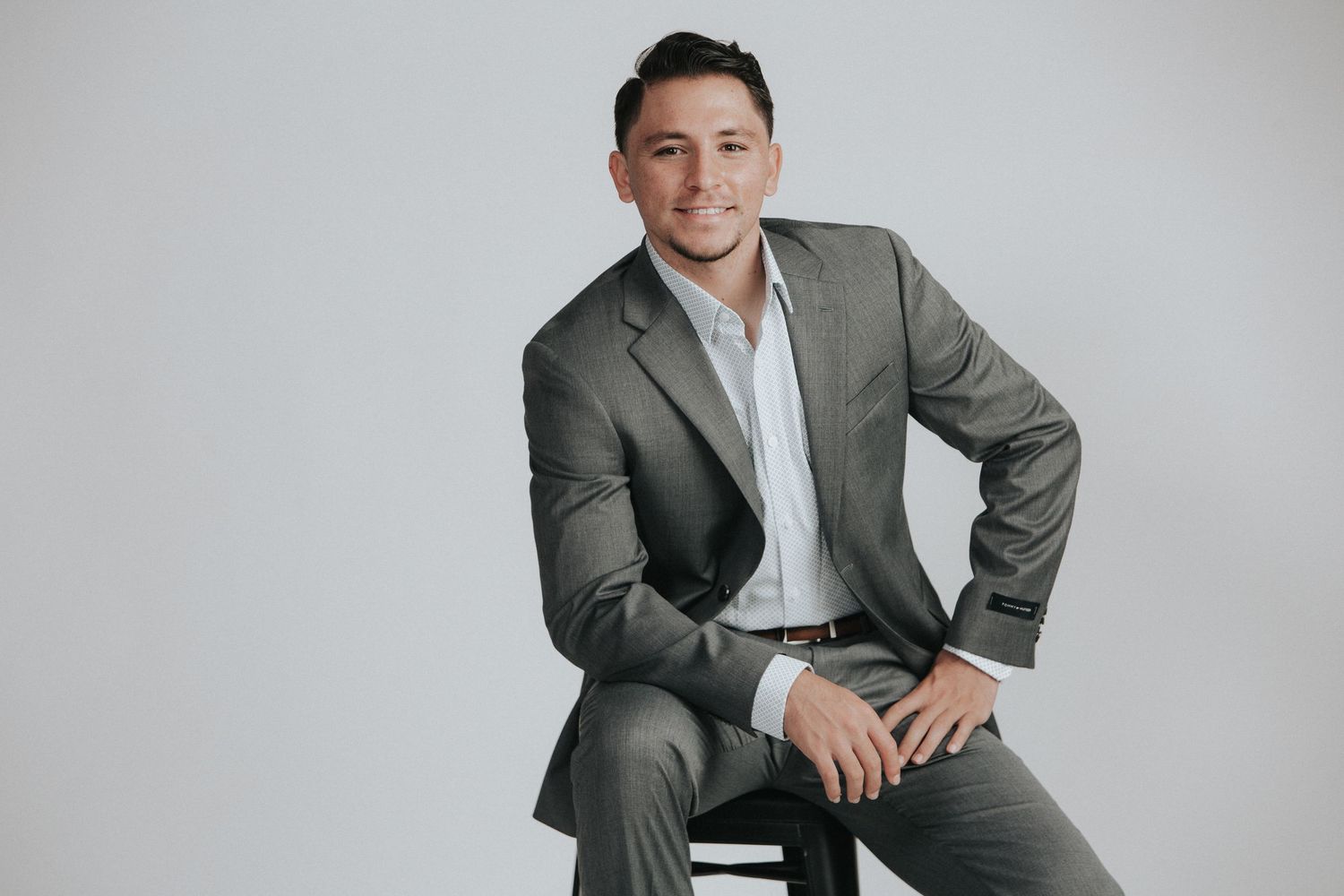 Three photos of someone posing in a grey suit and white shirt against a light grey background.