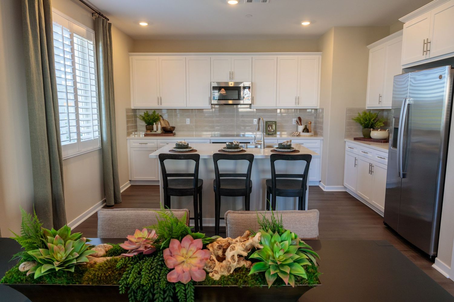 Modern open concept kitchen and dining area with hardwood floors, stainless steel appliances, and recessed lighting.
