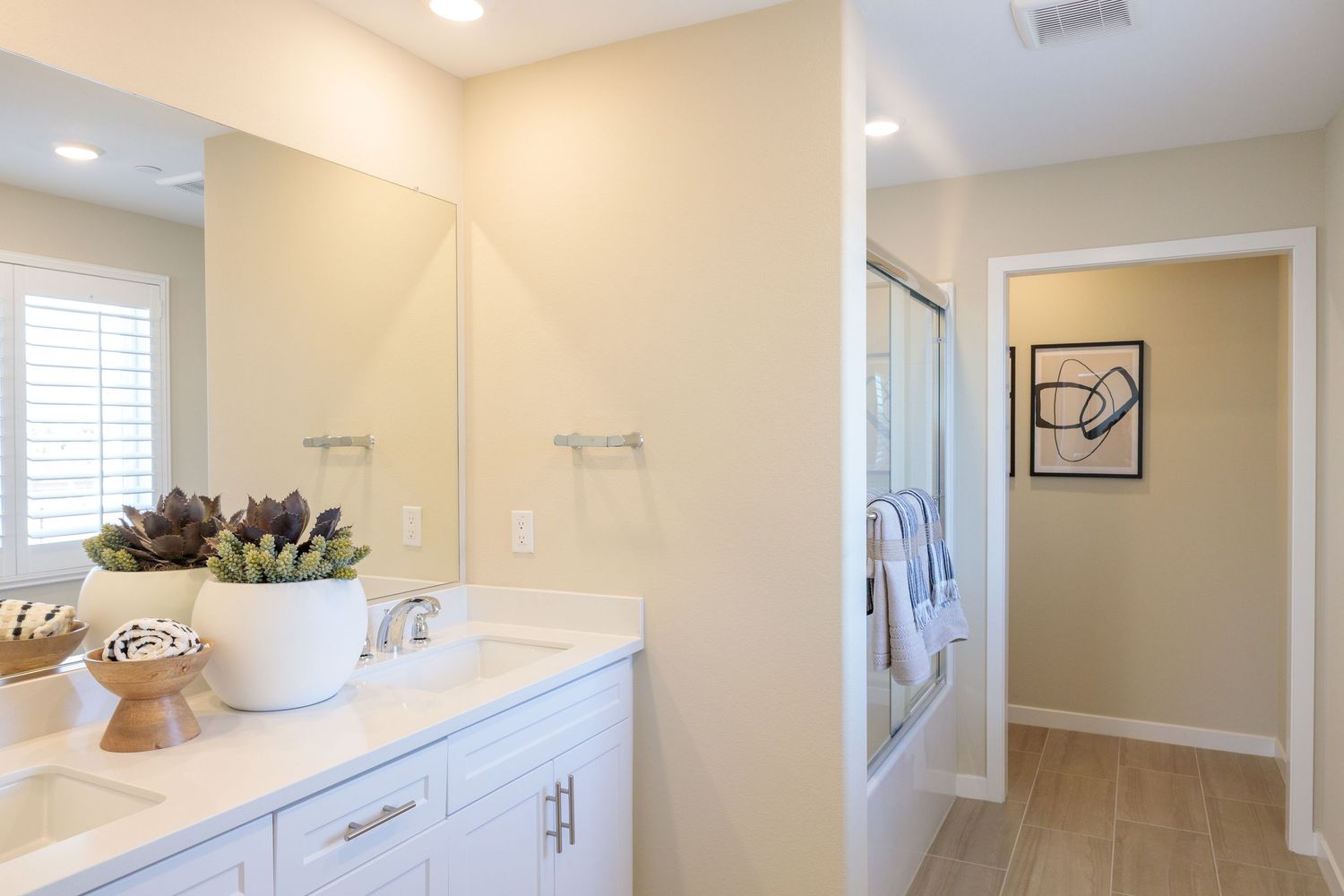 Modern bathroom interior with beige walls and white cabinets shown in multiple angles with recessed lighting.