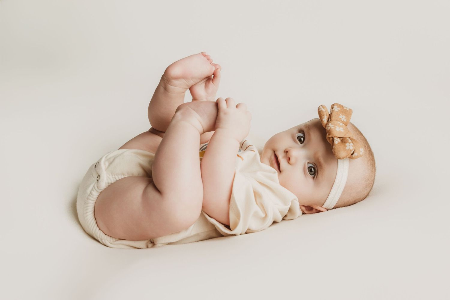 Series of five dreamy newborn photography shots showing baby lying on white blanket in artistic poses.