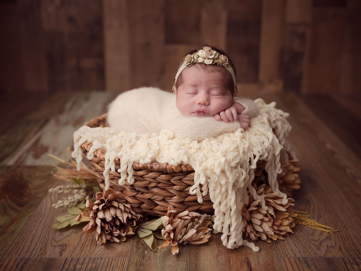 A series of sliding newborn photography images showing a sleeping baby nestled among pine cones and soft white fur.