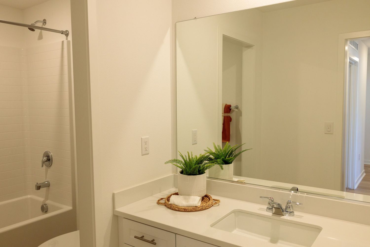 Modern white bathroom interior with vanity counter, large mirror, and shower curtain visible in reflection.