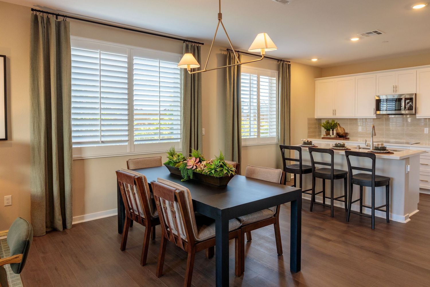 Modern open concept dining area with pendant lighting, wood floors, and large windows letting in natural light.