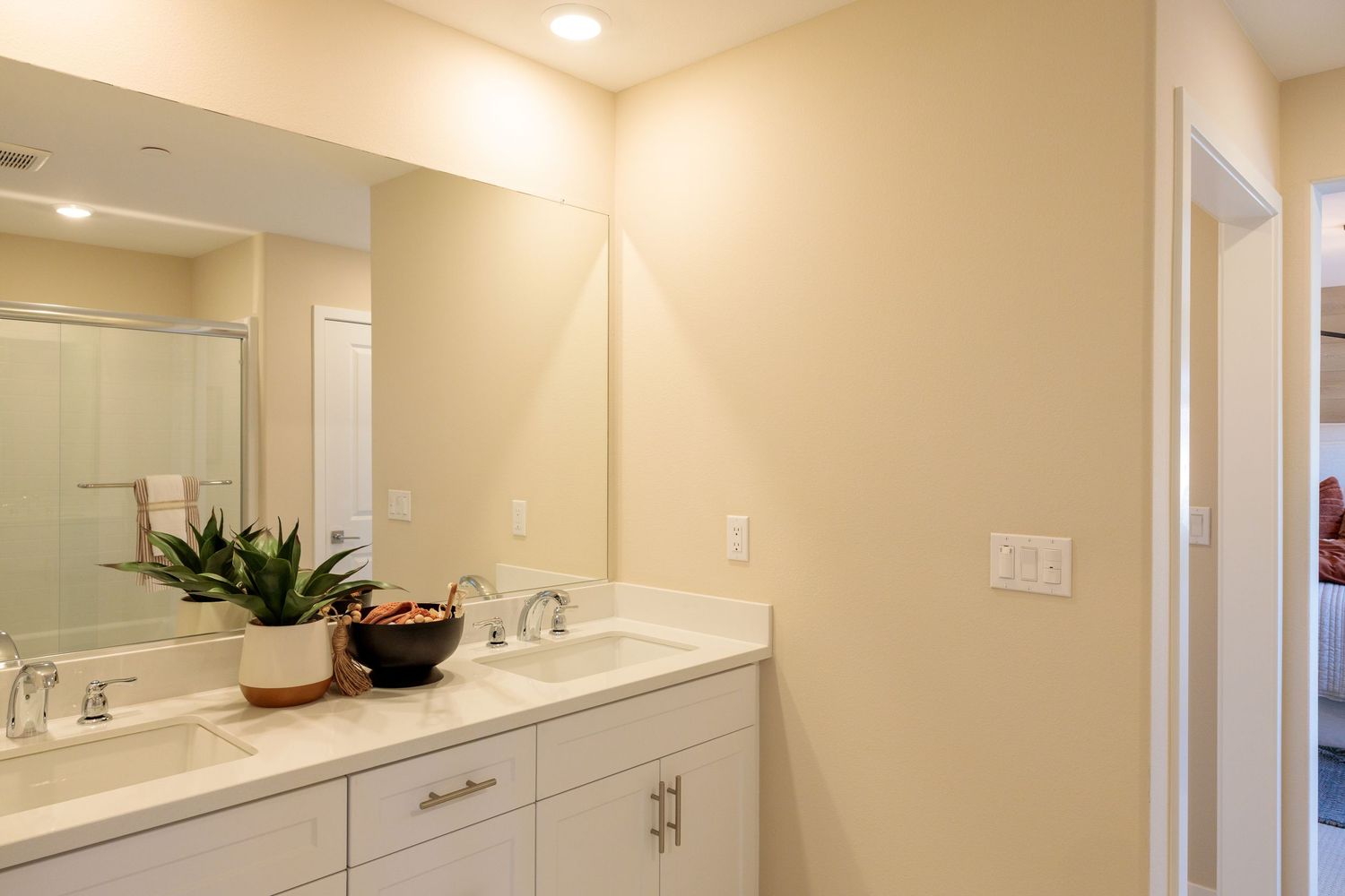 Modern bathroom interior with white countertops, beige walls and recessed lighting creating a bright, clean space.