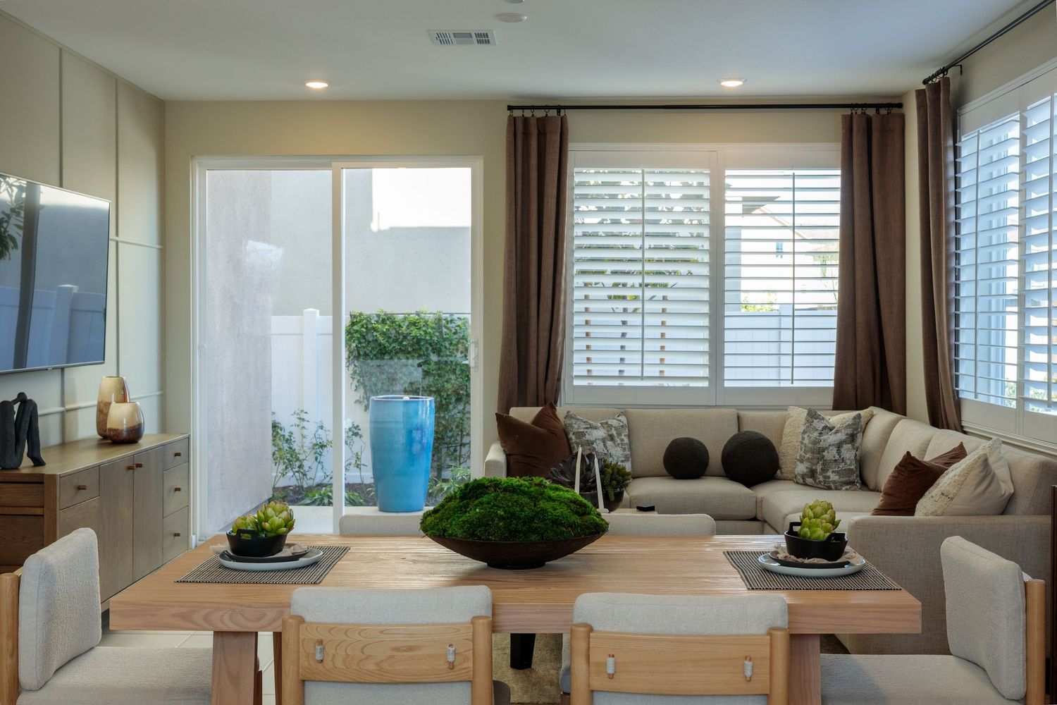 Modern living room interior with white walls, hardwood floors, and natural light streaming through multiple windows.