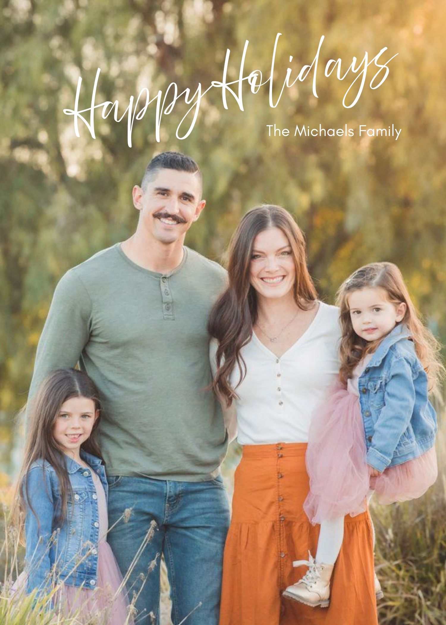 A family poses together outdoors in coordinated outfits during a fall photo session with autumn foliage in the background.