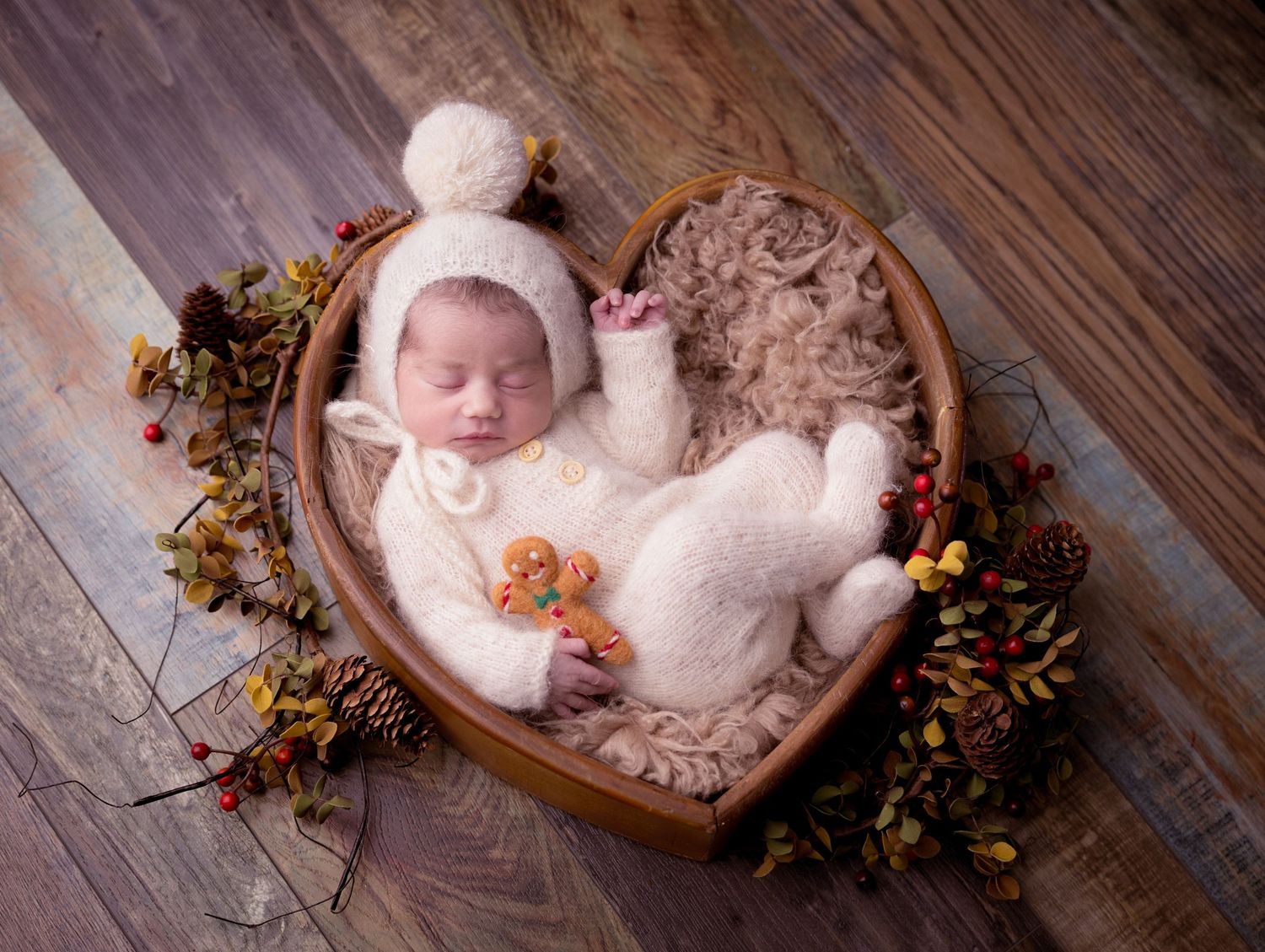 newborn photography pose featuring a sleeping baby in heart-shaped wooden bowls with rustic christmas decor.