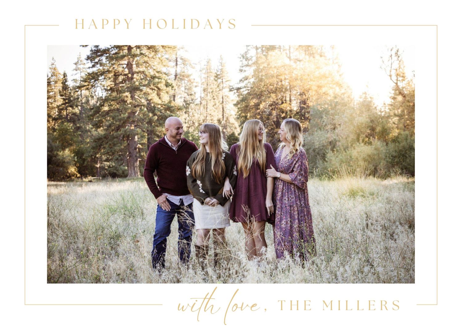 A group in coordinated purple and brown outfits poses together in a sunlit field during golden hour for holiday photos.