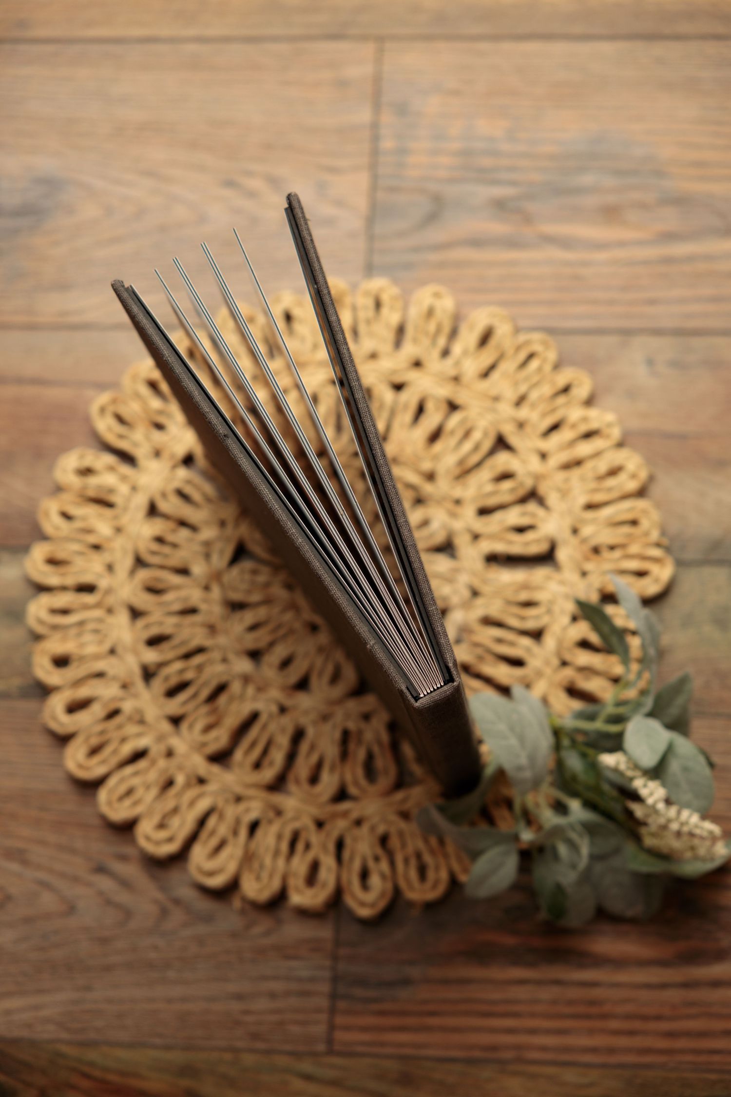 A series of wooden fan decorations with black spokes and eucalyptus leaves arranged on a rustic wooden surface.