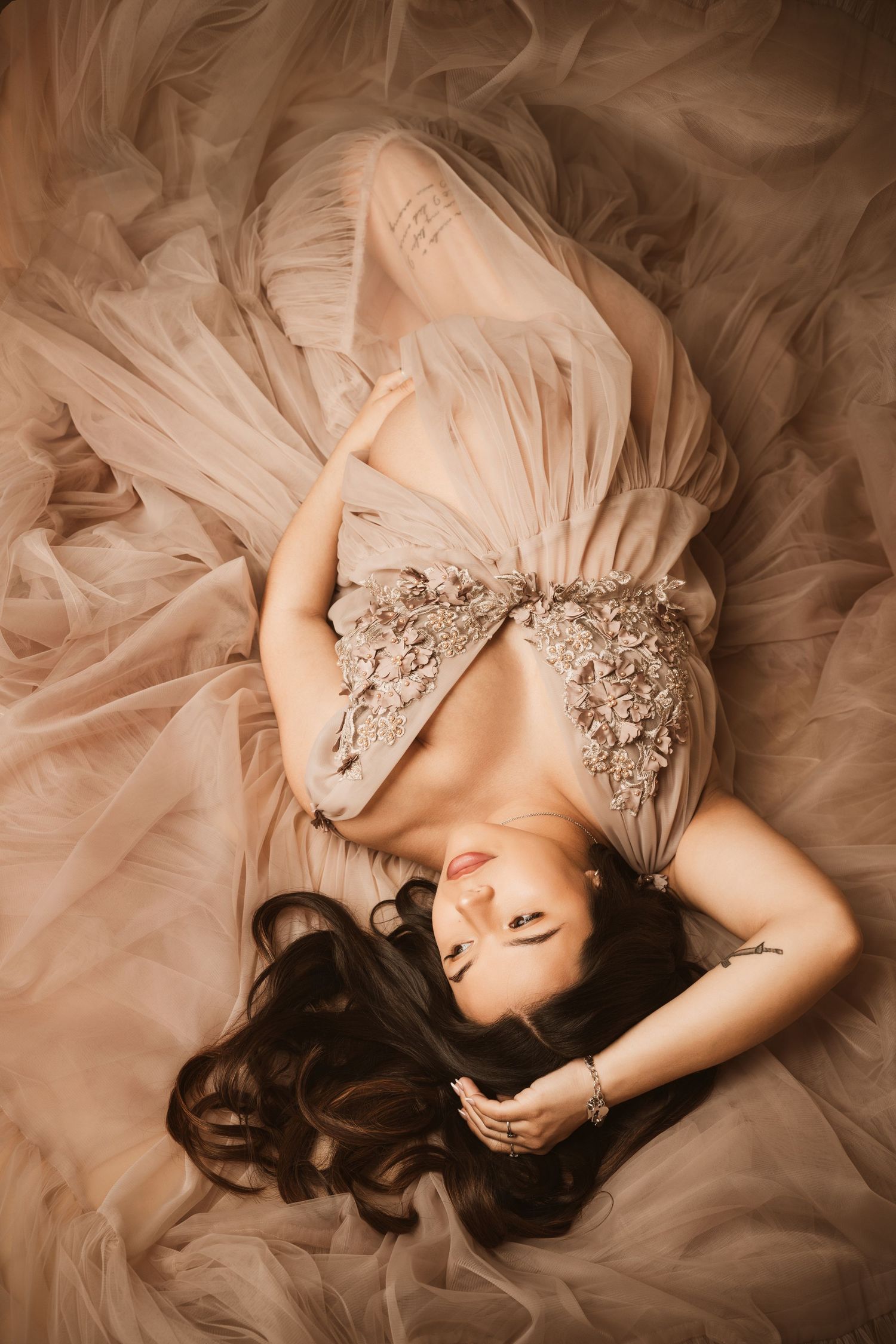 A series of dreamy sepia-toned photos showing a figure lying gracefully in layers of flowing tulle fabric.
