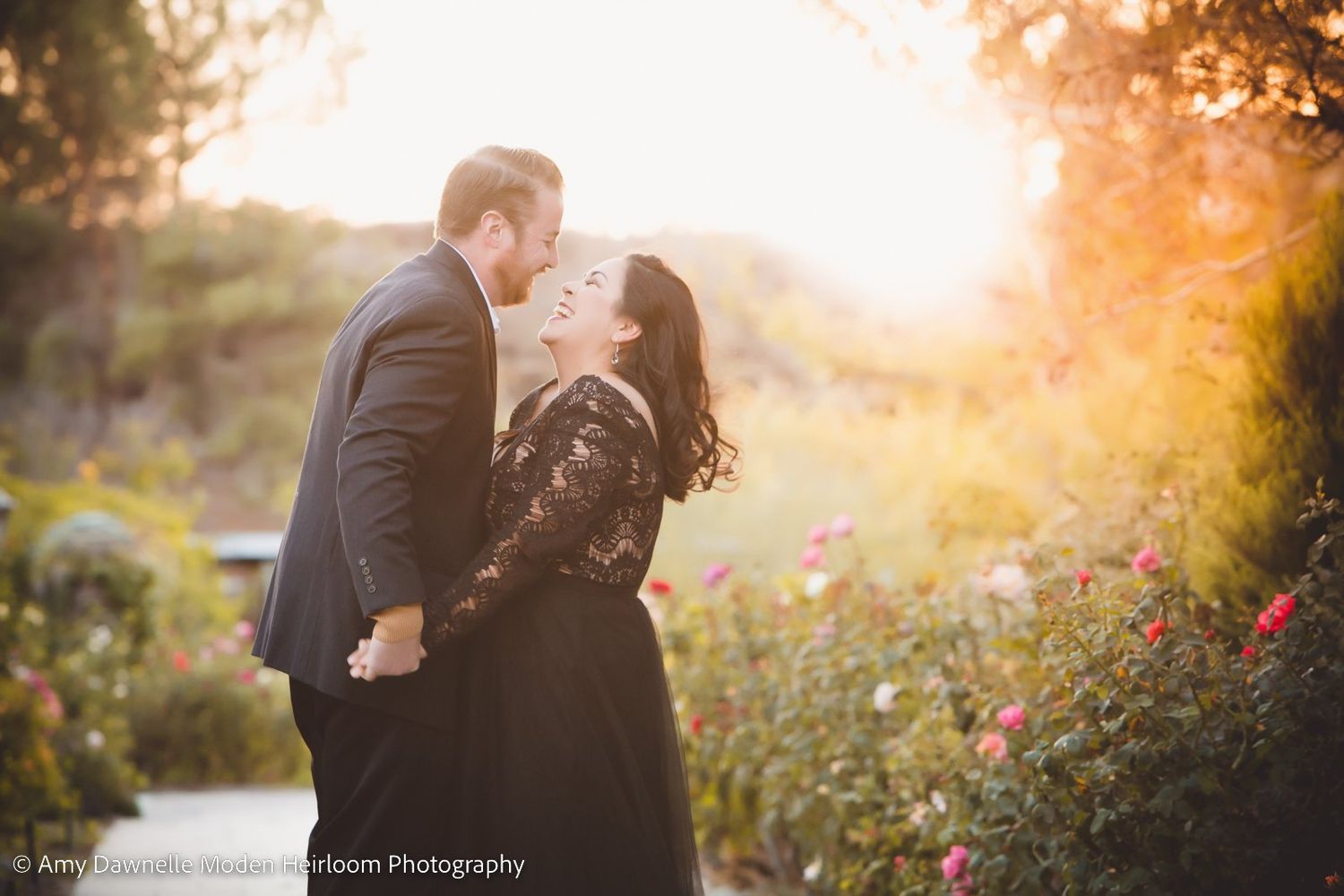 Romantic garden portrait of couple surrounded by flowers at sunset.