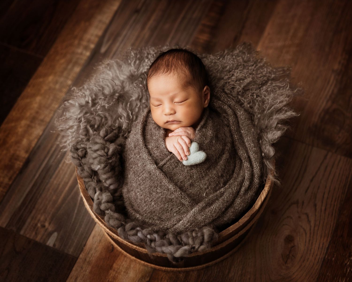 A series of newborn photography portraits showing a sleeping baby in dark brown tones on wooden surfaces.