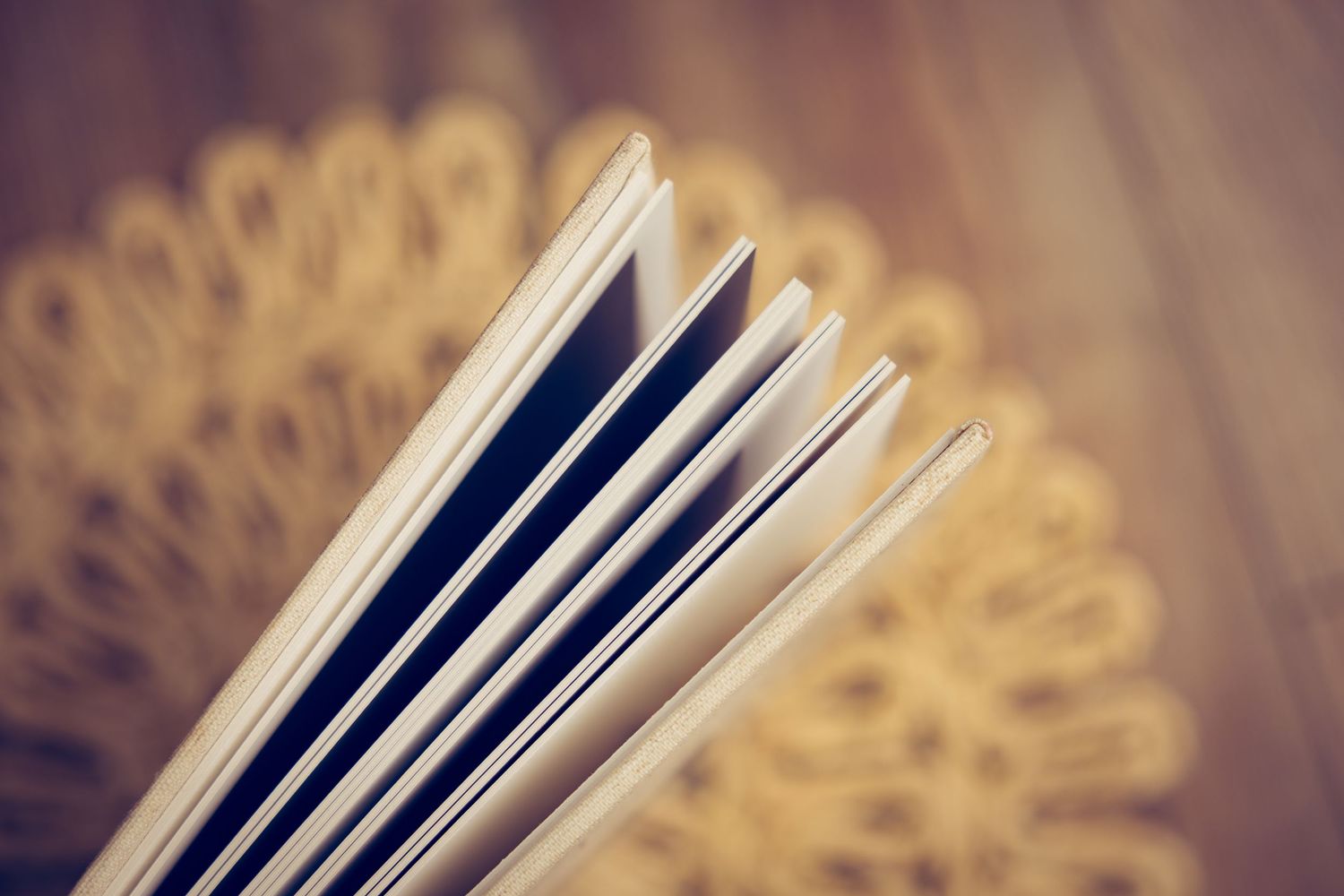 Book pages fanned out in a repeating pattern creating an abstract circular design against a dark background.