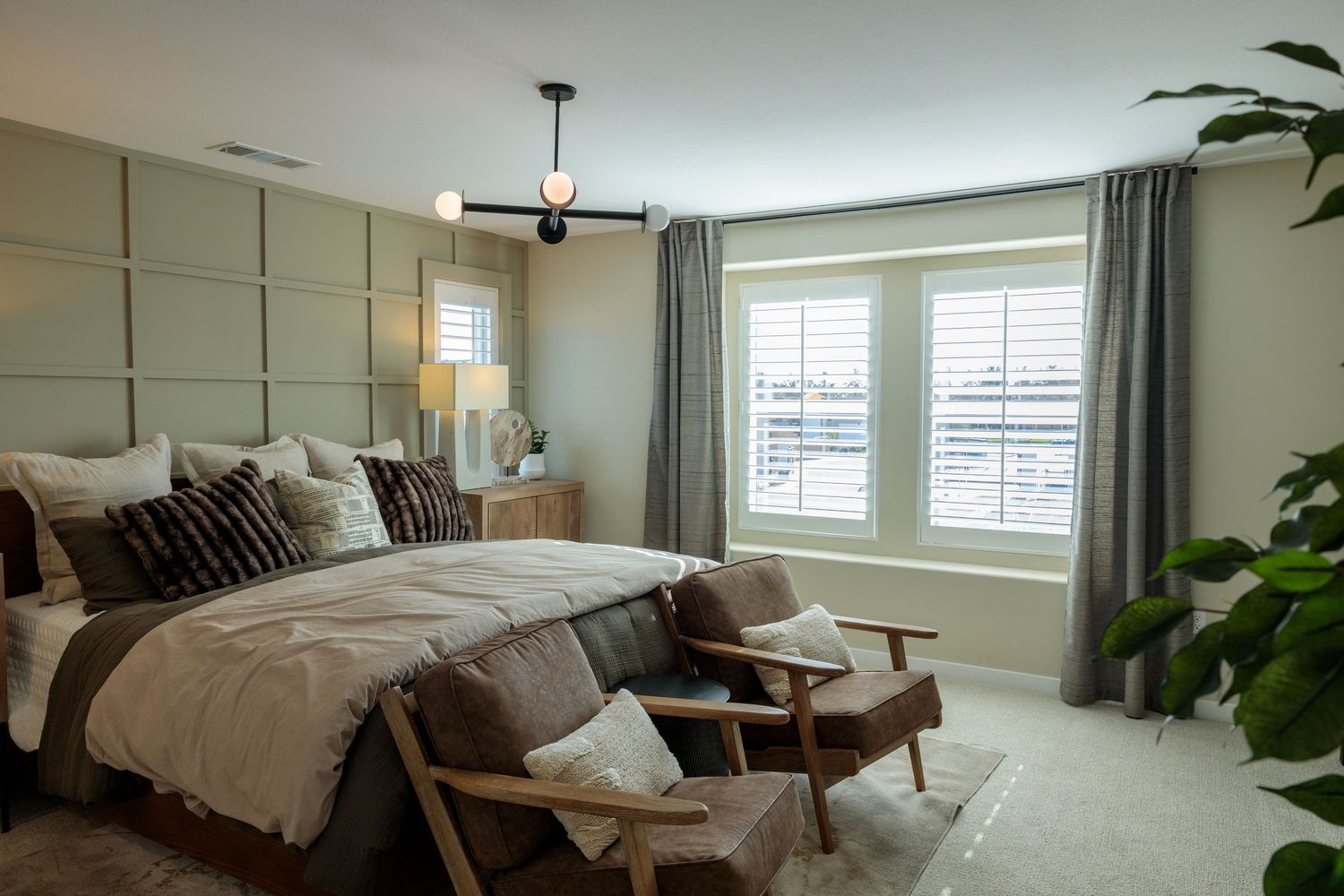 Spacious contemporary bedroom with large windows, neutral tones, and indoor plants showcases minimalist design.