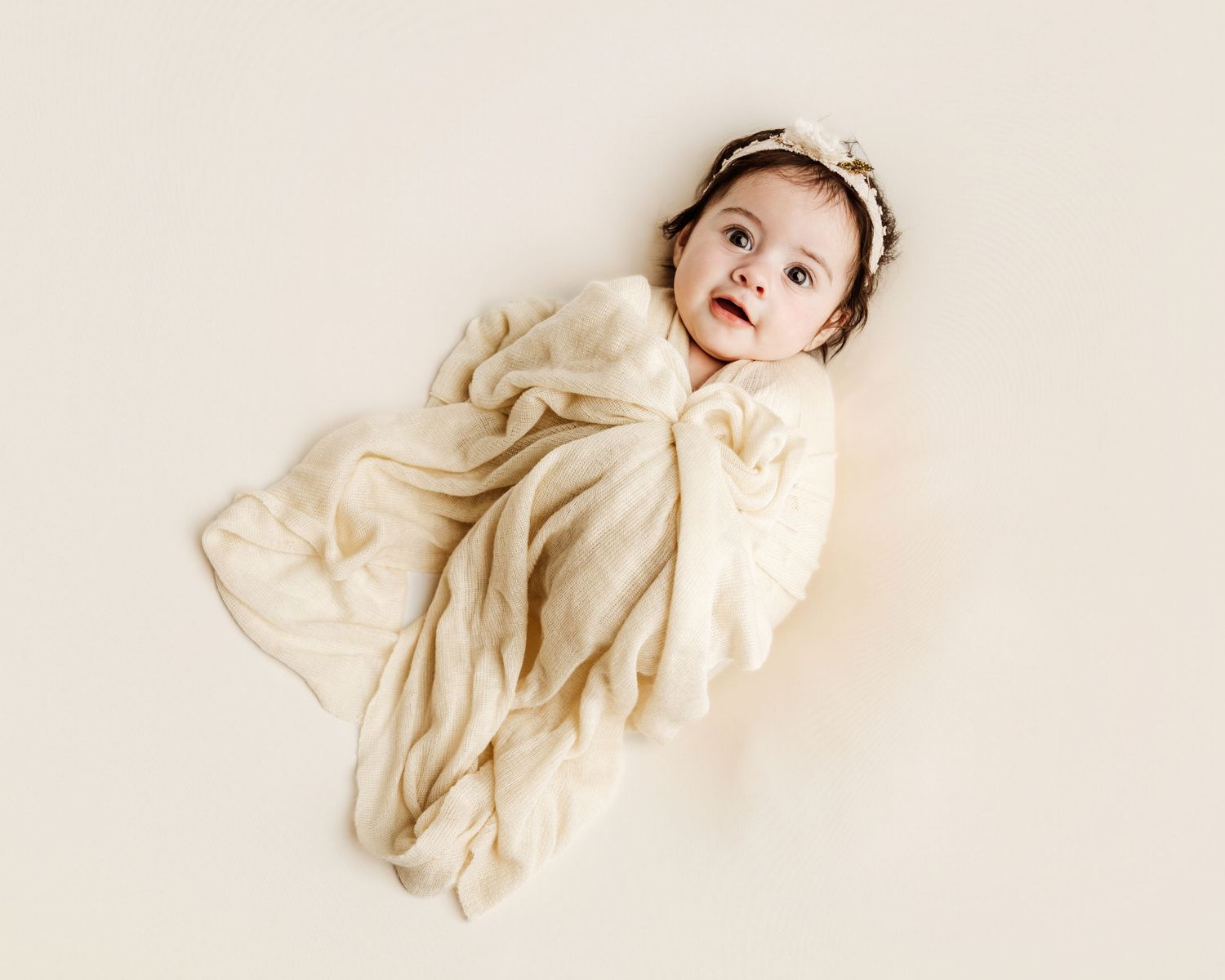 A series of four artistic photographs showing flowing white fabric against a light beige background.