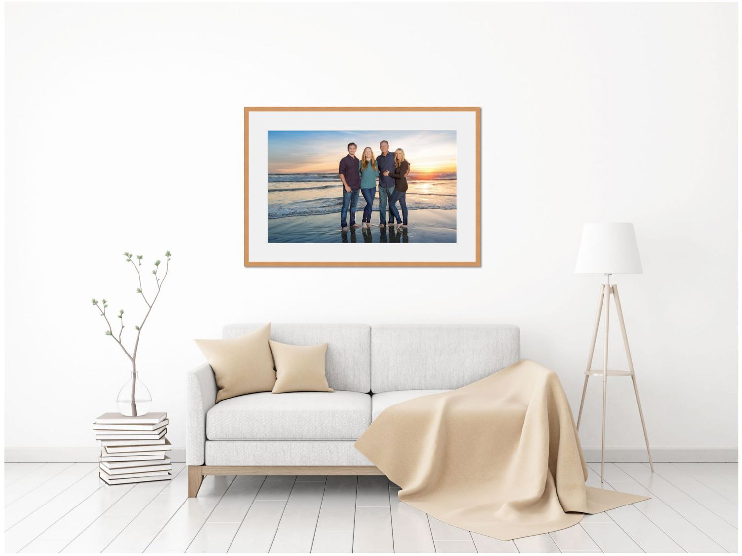 A framed photograph on a white wall above a light gray couch with beige pillows and throw blanket.
