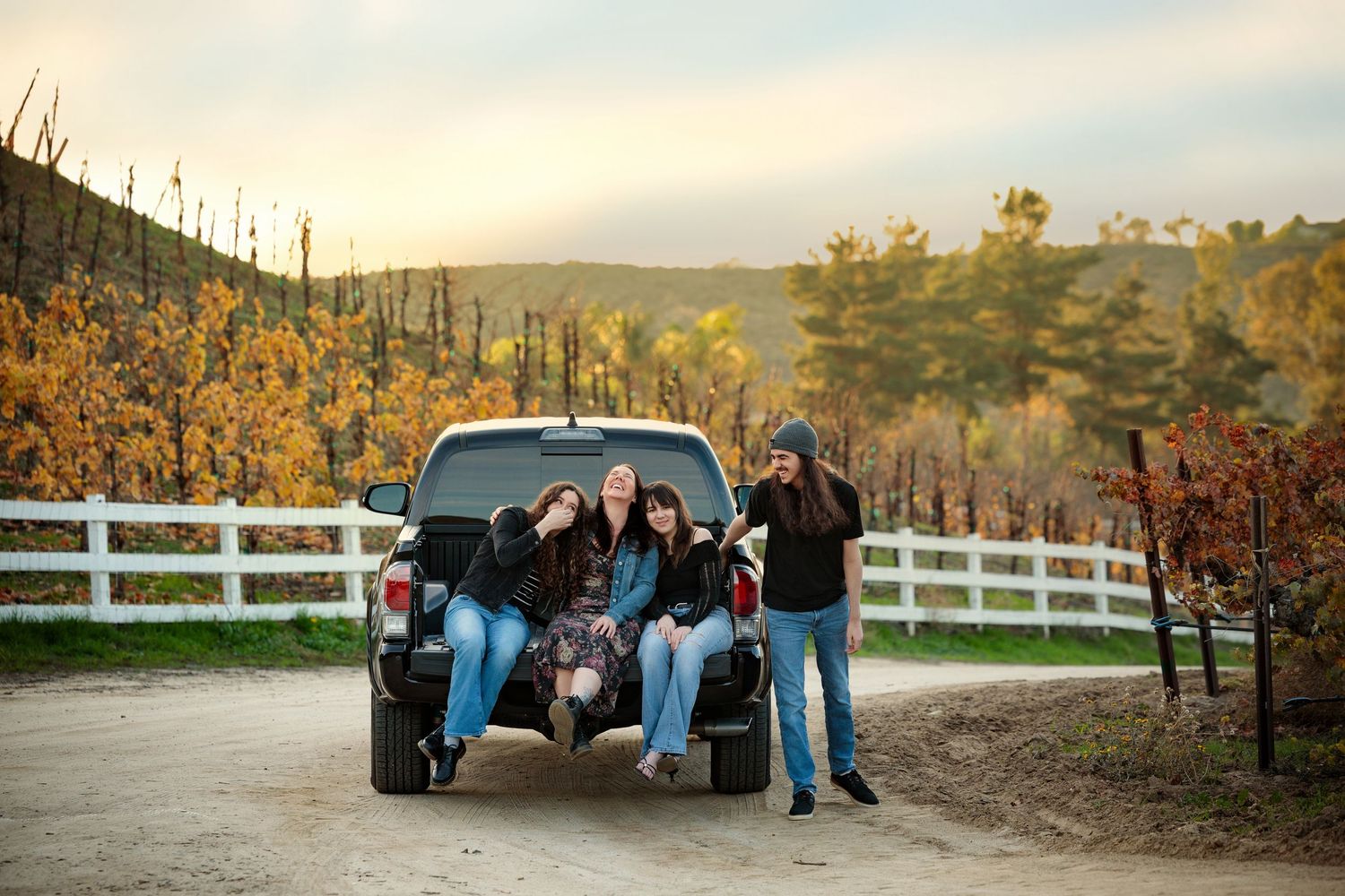 A series of wedding party photos taken outdoors during golden hour with white fences and autumn foliage in the background.