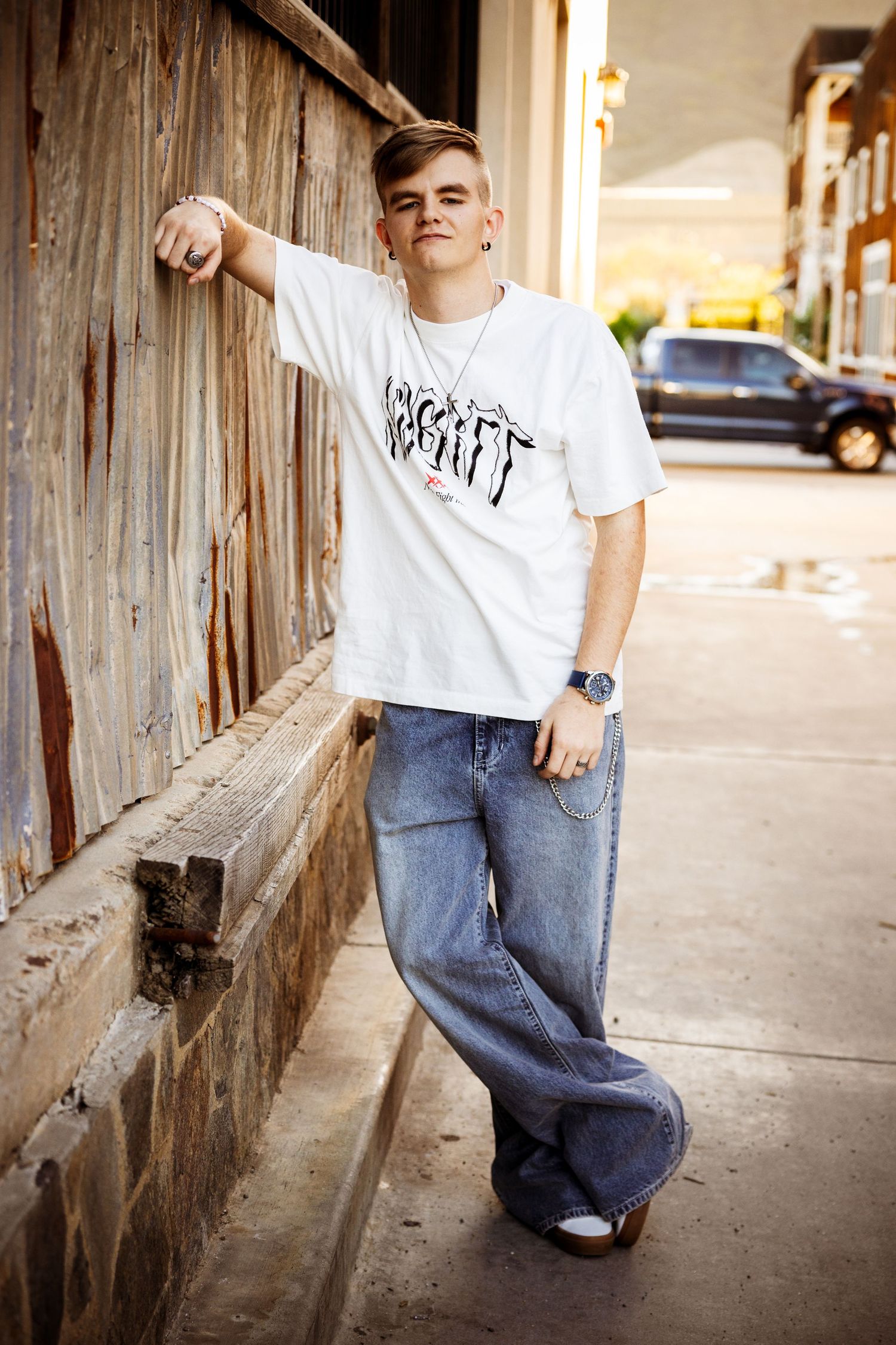 A sequence of four urban street photos showing someone in a white t-shirt and baggy jeans posing against a wall.