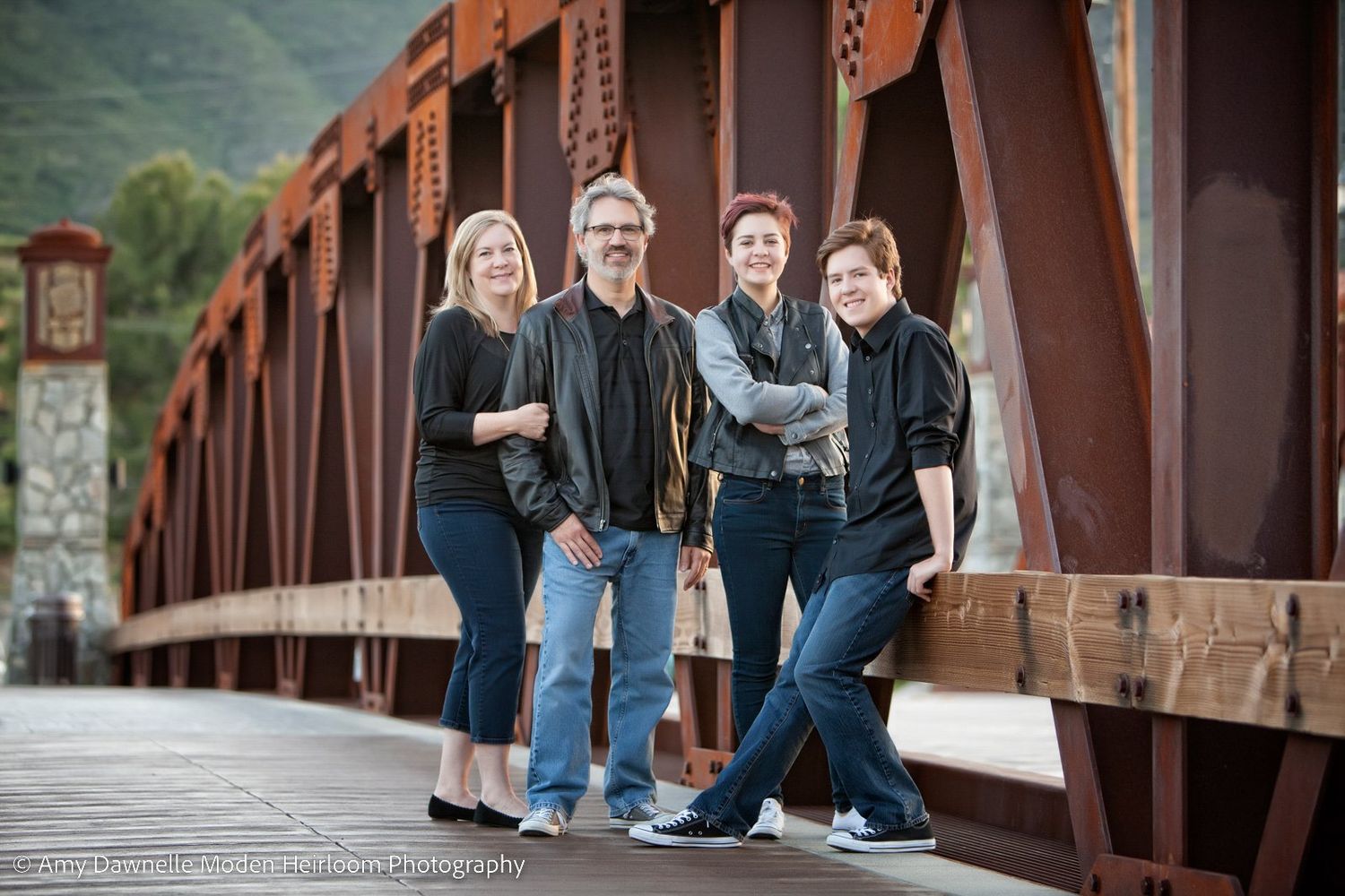 A group portrait of four people standing on a rustic metal bridge.