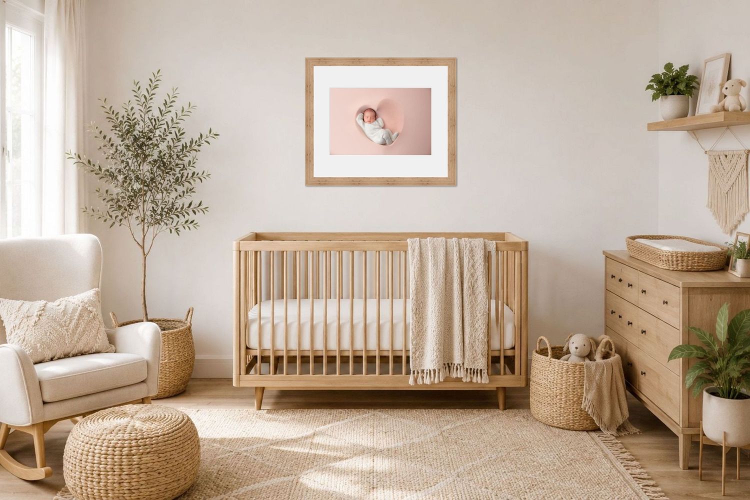 Serene nursery with wooden crib, rocking chair, olive tree, and framed newborn photo on a soft pink wall.