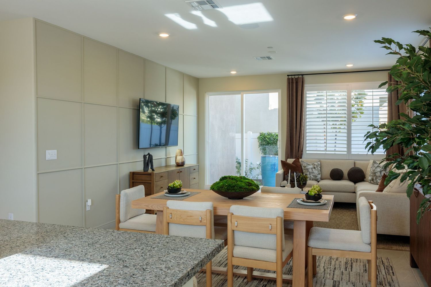 Modern open concept living space with natural light, skylights, wood furniture, and potted plants in a bright interior.