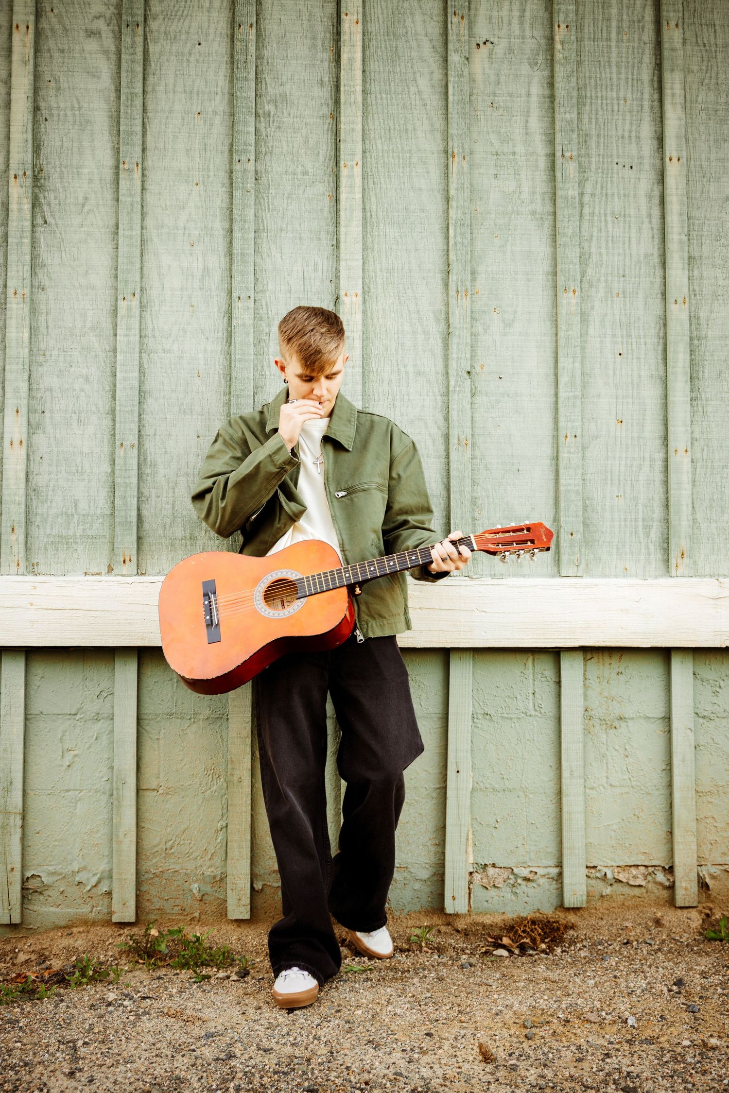 Creative panoramic sequence of a guitarist playing acoustic guitar against a weathered wooden fence.