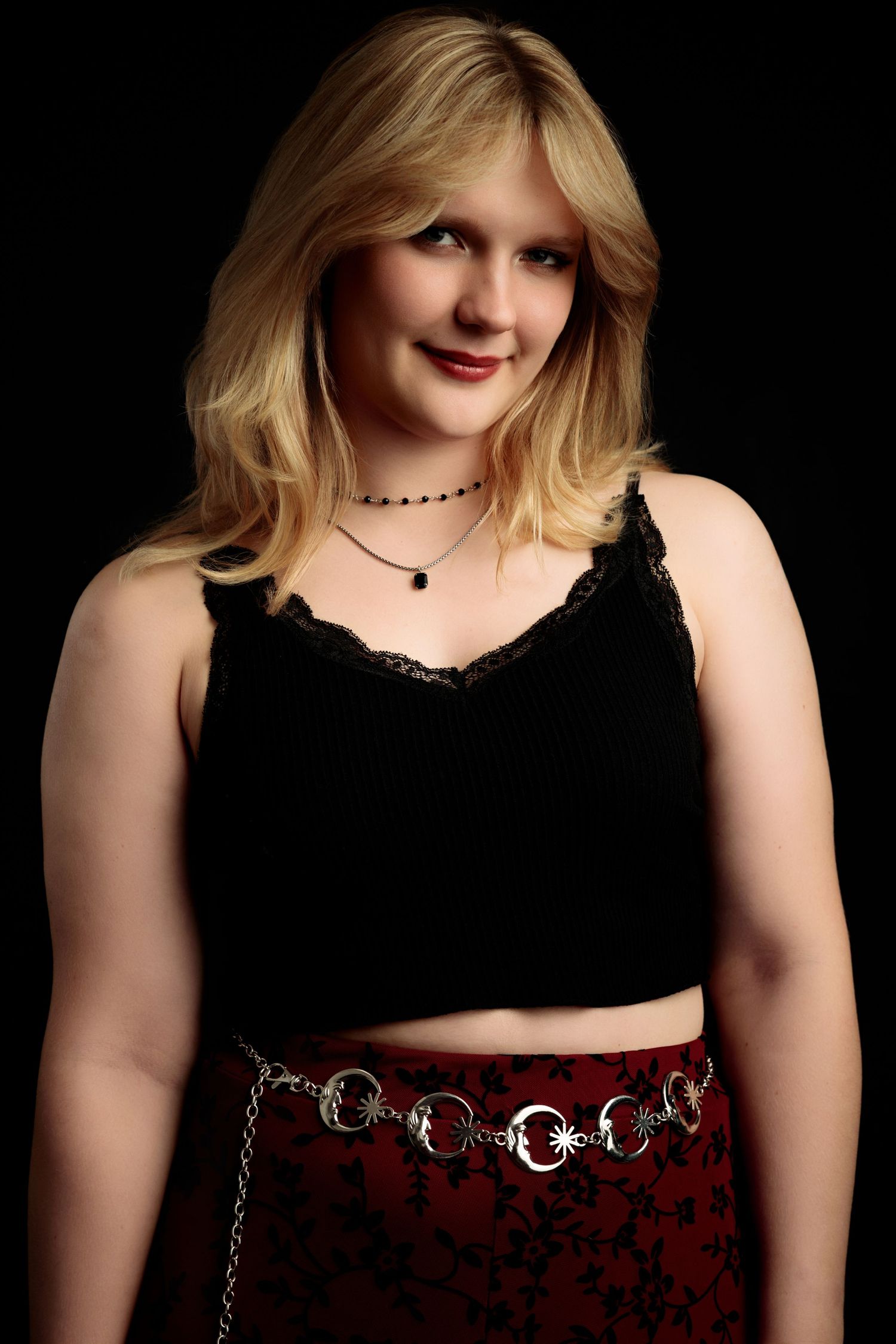 Professional portrait series showing different poses in black attire with a decorative chain belt against dark background.