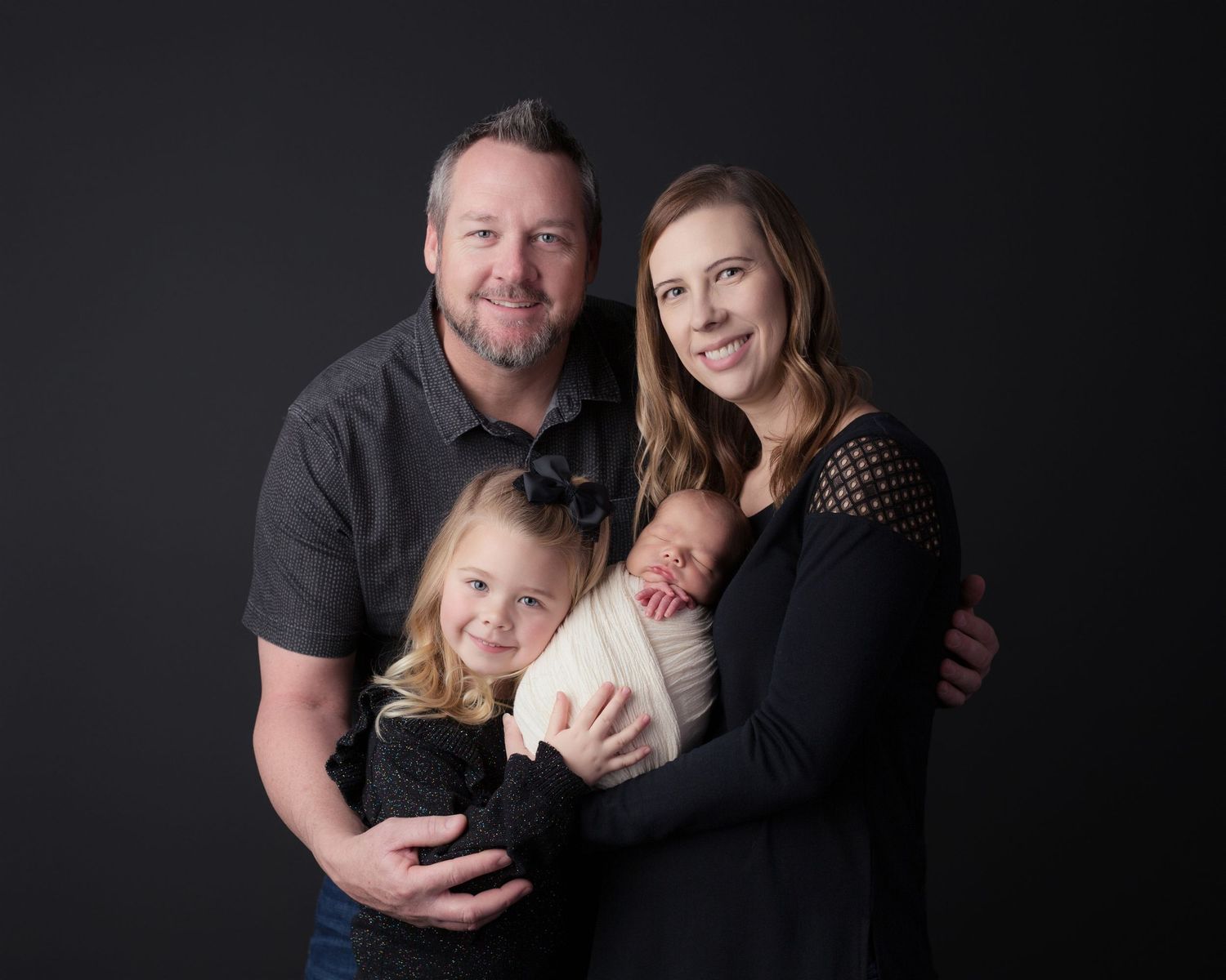 A series of professional family portraits on a black background featuring tender embraces and warm smiles.