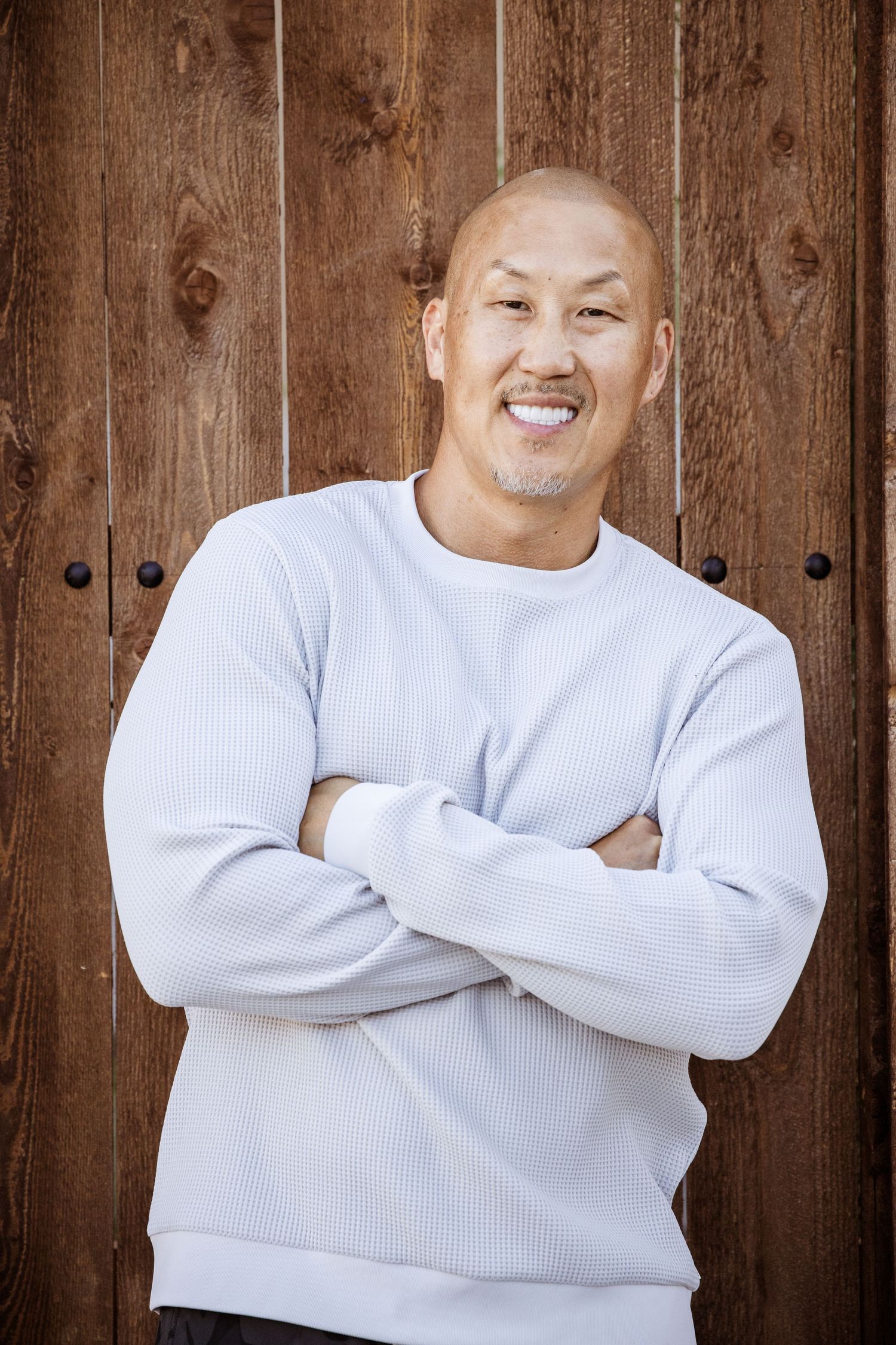 A sequence of photos shows a person in a white sweater posing with crossed arms against a wooden wall background.