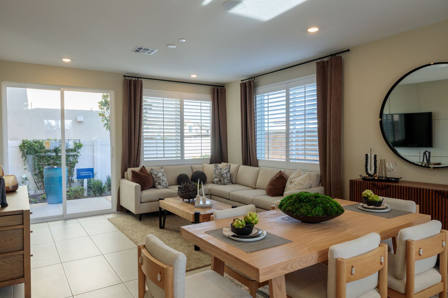 Modern coastal living room with beige sofa, wood coffee table, and large windows offering panoramic ocean views.