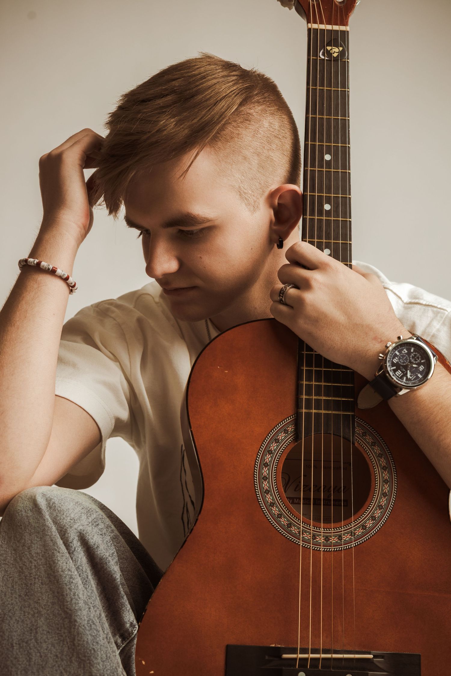 Artistic portrait series showing a person with an acoustic guitar against a light background.
