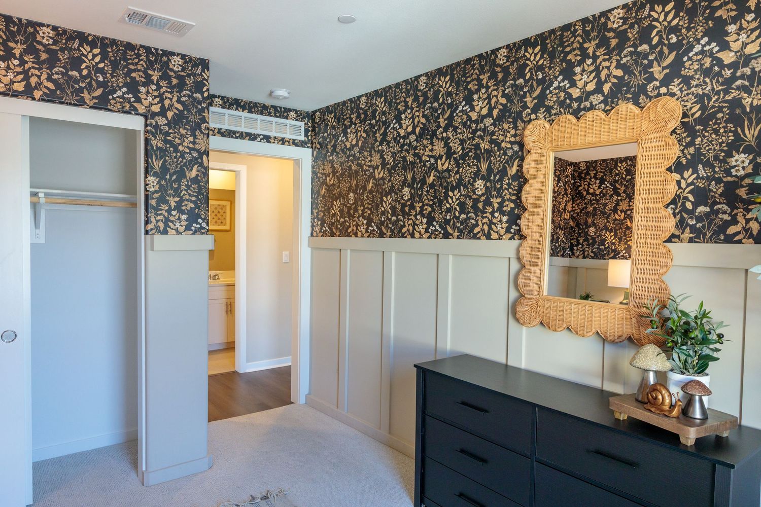 Modern hallway features dark floral wallpaper, white trim, and hardwood flooring with multiple doorways.