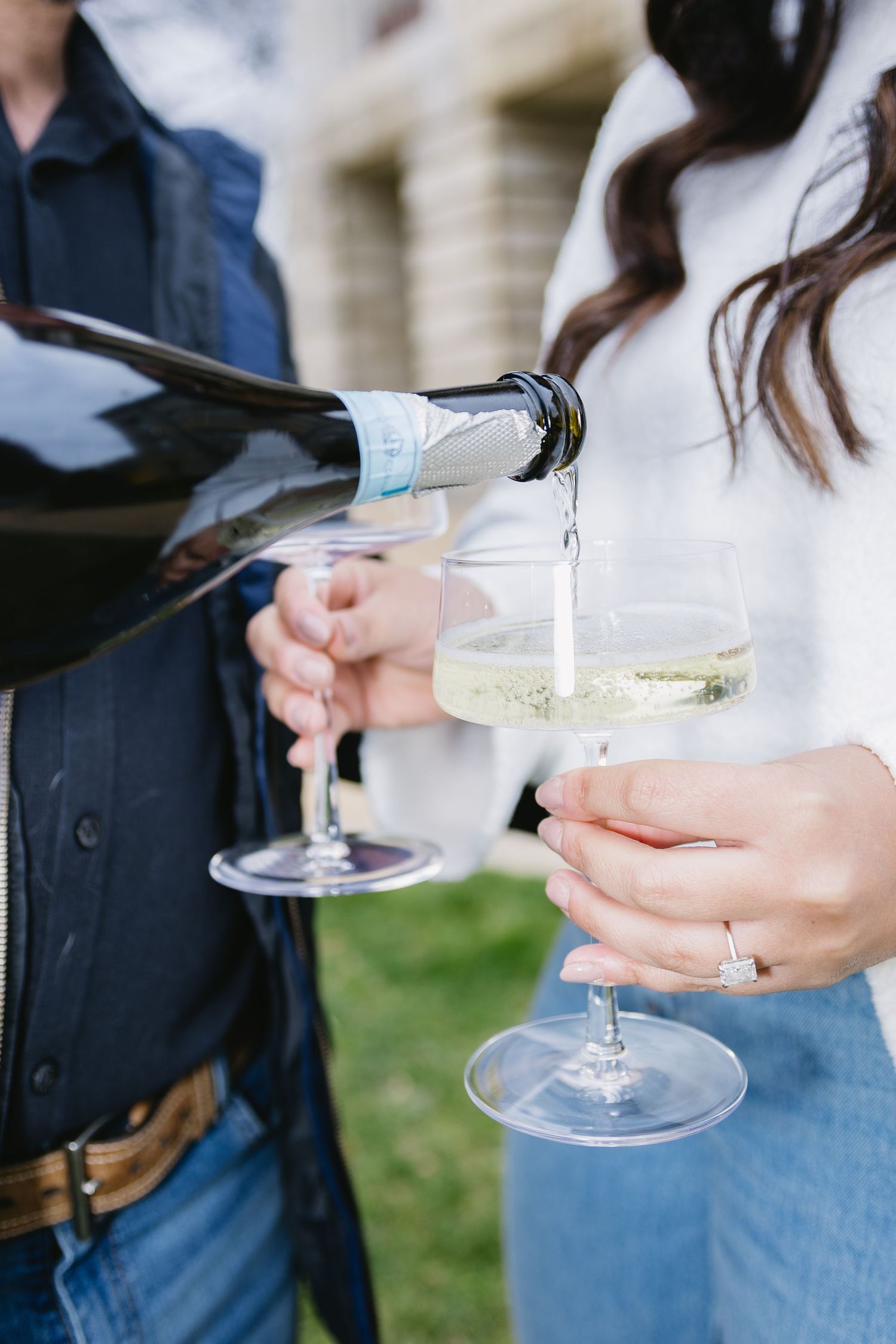 Champagne being poured into elegant glasses at an outdoor celebration.