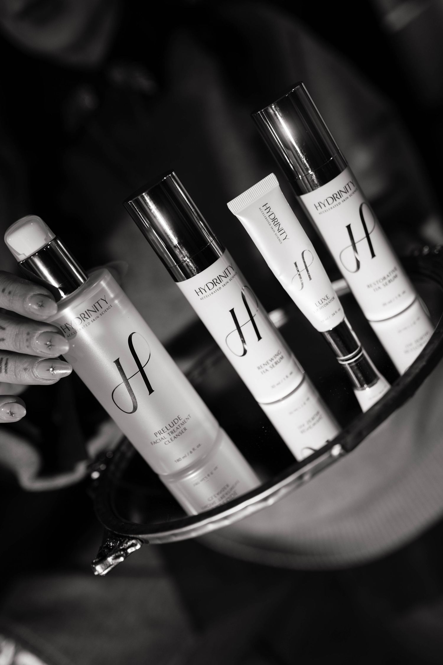 Black and white photo series showing wine bottles on display with elegant cursive labels in moody lighting.