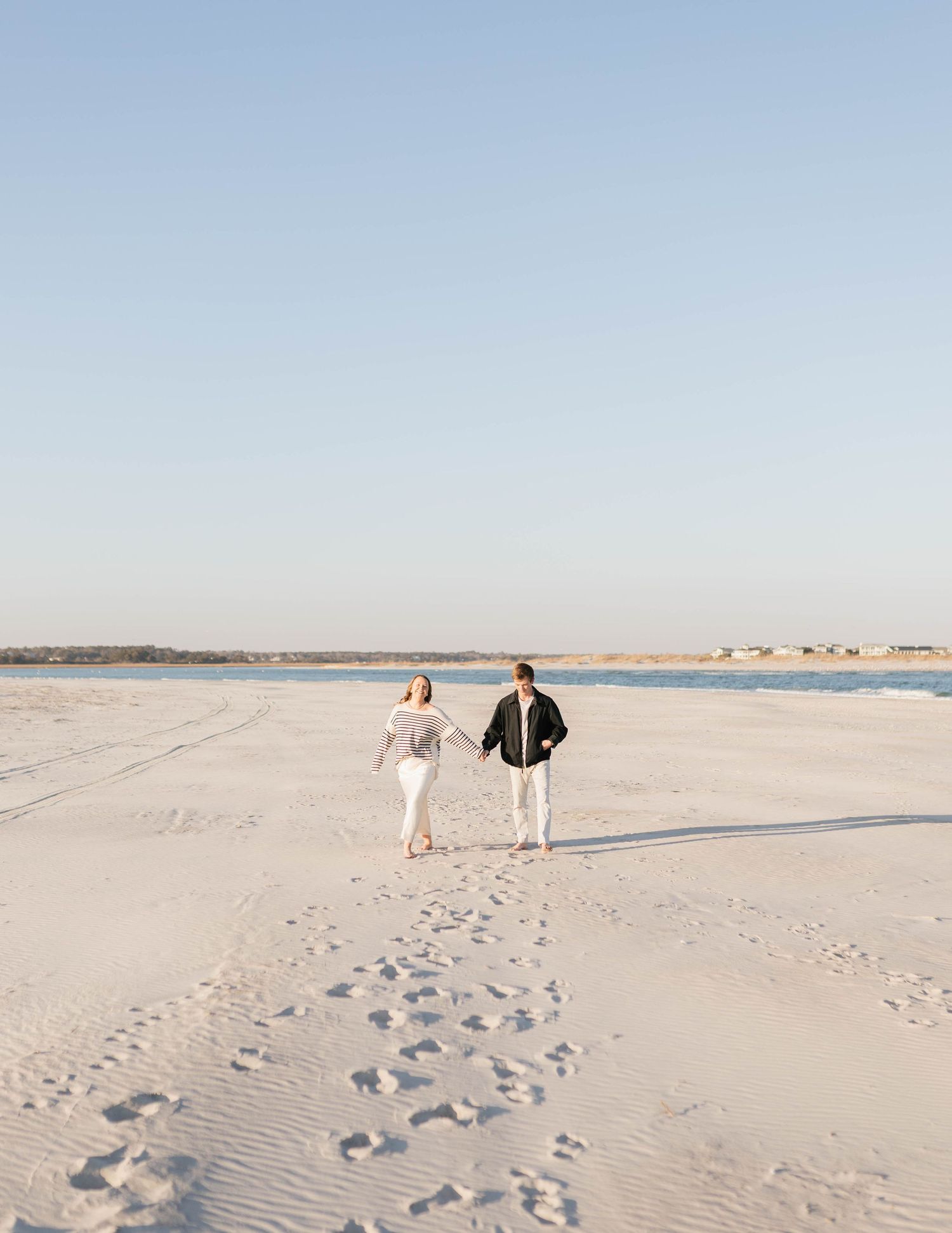 Ethereal desert landscape with soft white sand dunes stretching to the horizon under a pale blue sky.