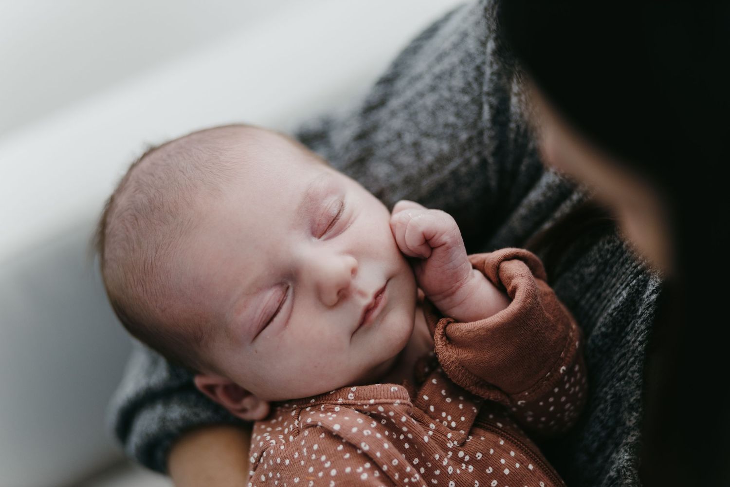 Close-up of sleeping newborn baby wrapped in brown clothing.
