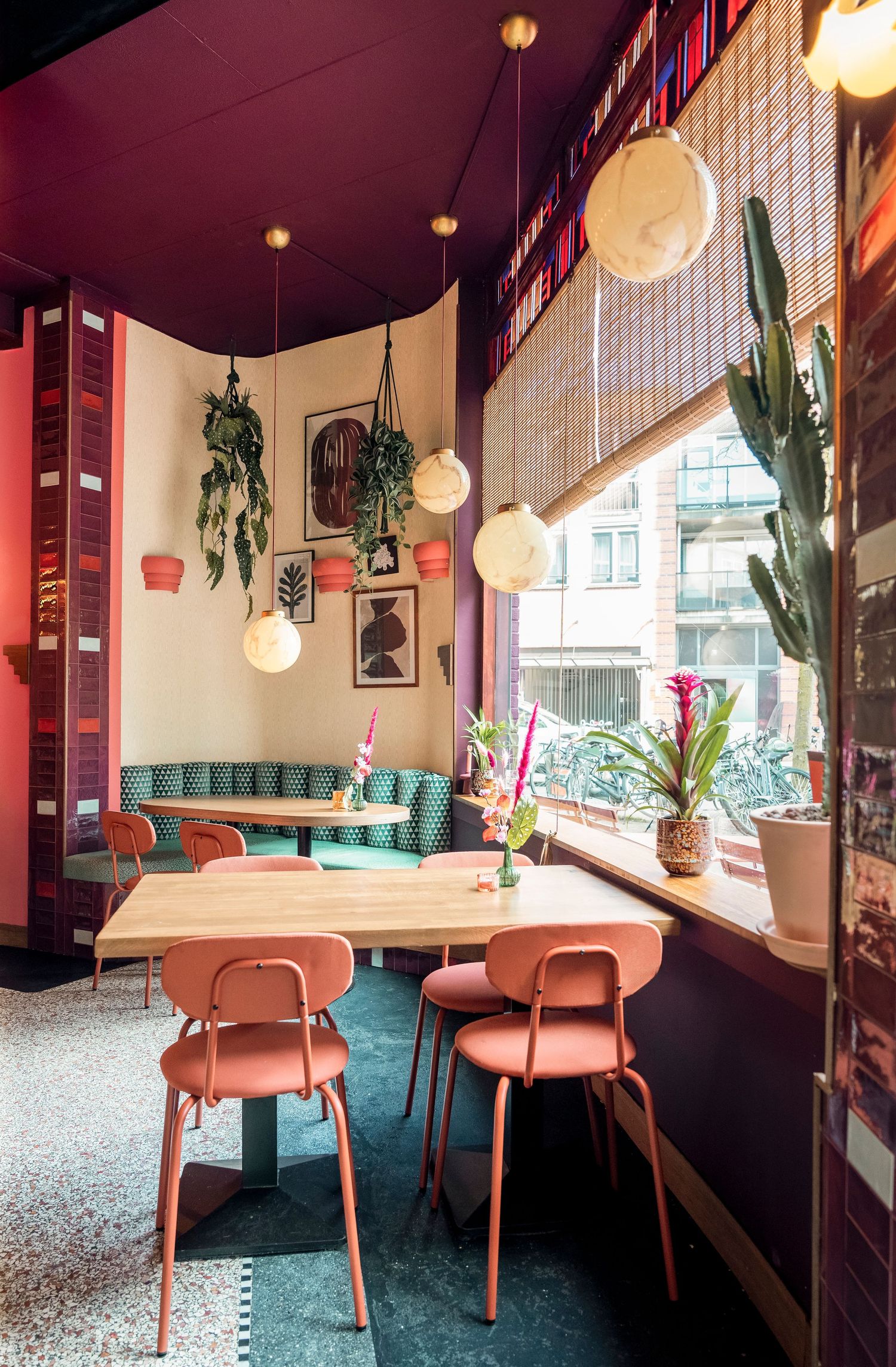 Overzichtsfoto van een paar tafel in het restaurant en luxe ronde bank met planten erboven. Gezellig, kleurrijk en tegeltjes aan de wand