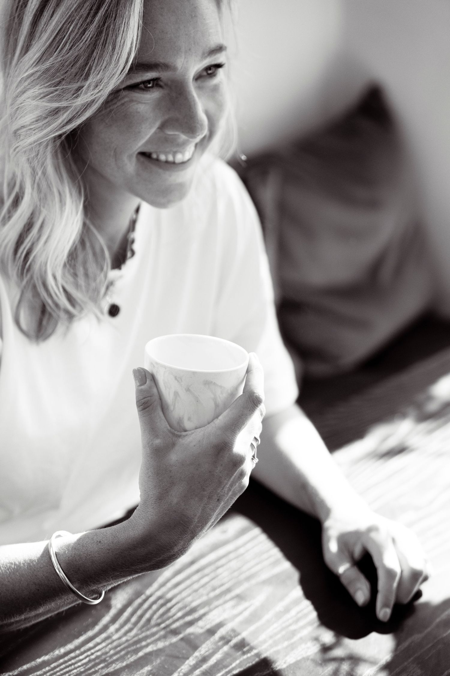 Portret van een vrouwelijke coach met koffie kopje in de hand, lachend in zwart/wit.