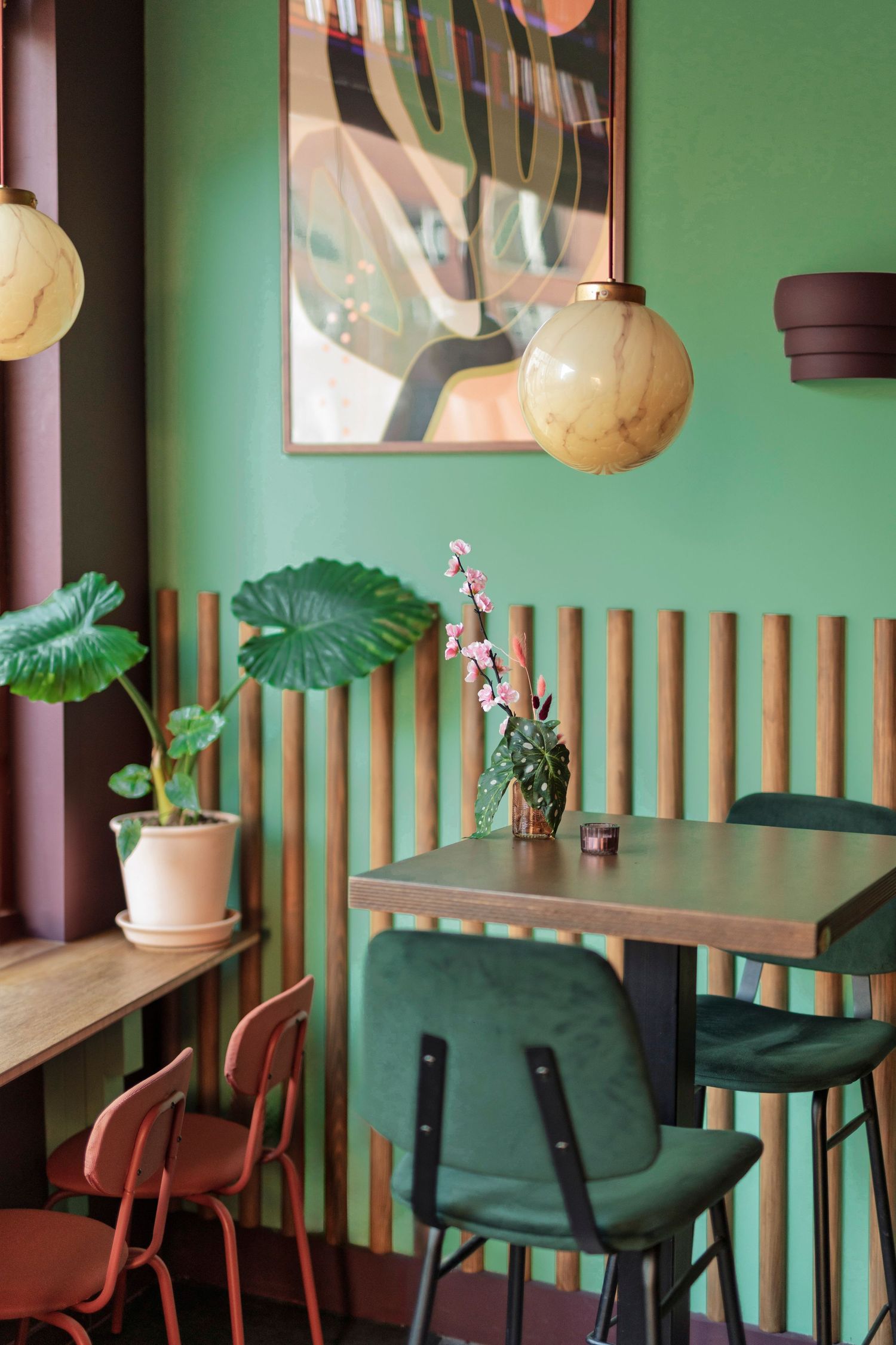Overzichtsfoto van een tafeltjes en bar aan het raam. Met planten, schilderijen aan de wand en veel kleur. Puerto Burrito interieur shoot.