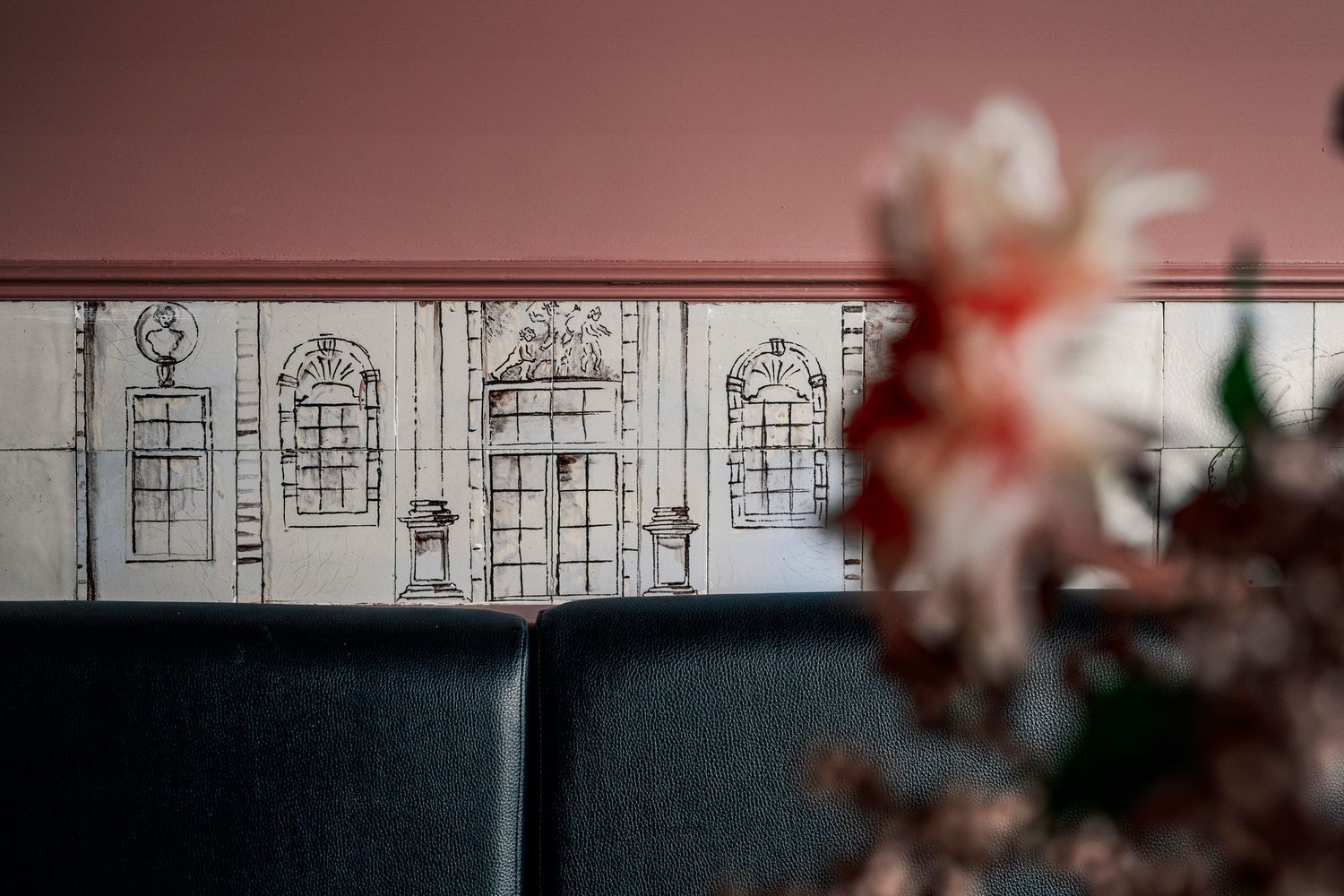 Sfeervolle wand in Heyu Café met tegeltjes en kleur roze  – een uitnodigende, persoonlijke ambiance.