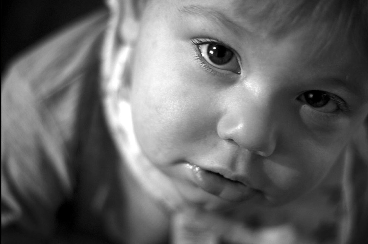 Acurious child looking up at the camera, captured in a playful moment during a portrait session in Prestwich, Manchester