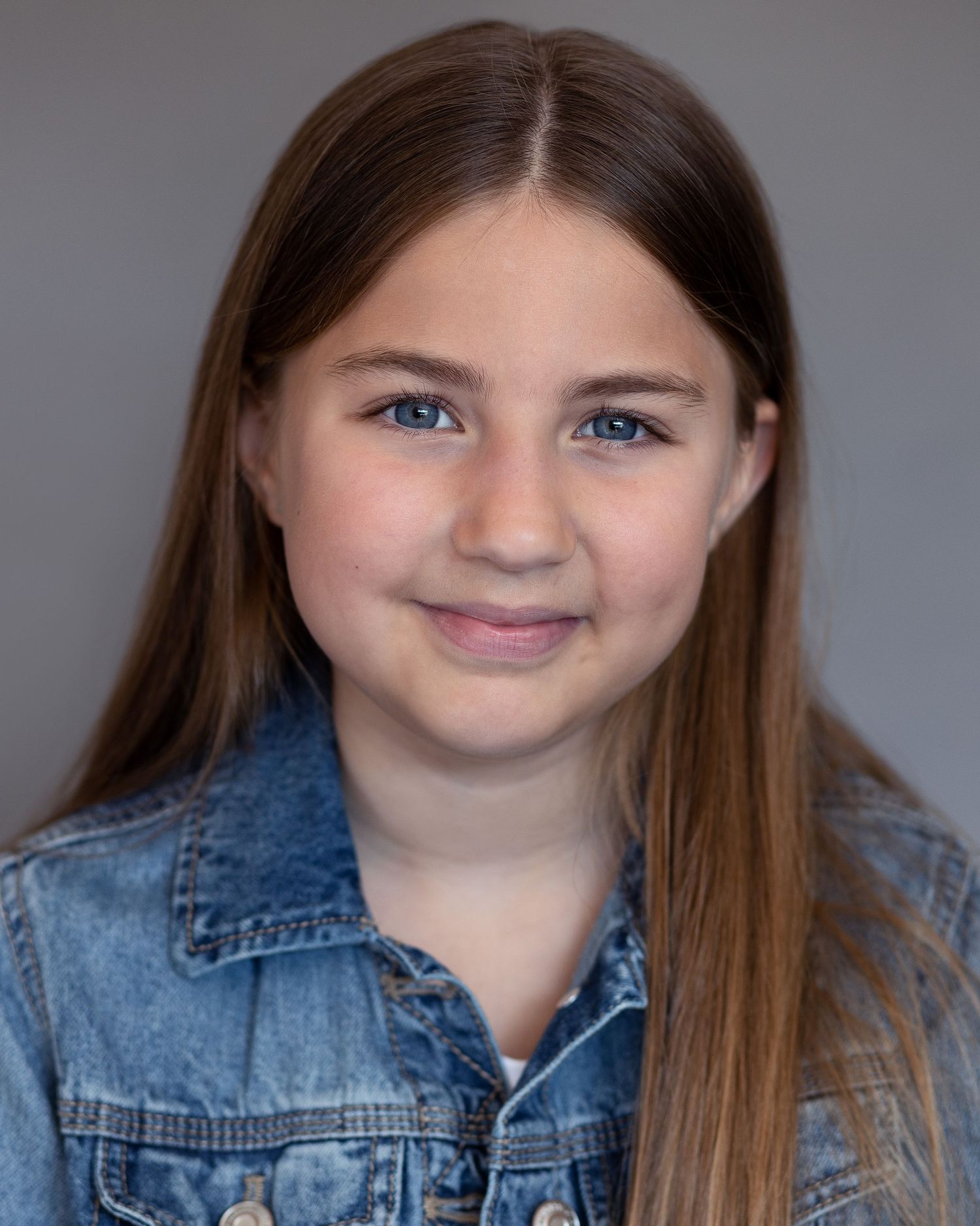 A young girl with her hair down smiling for an acting headshot in Prestwich, showcasing confidence during a professional session