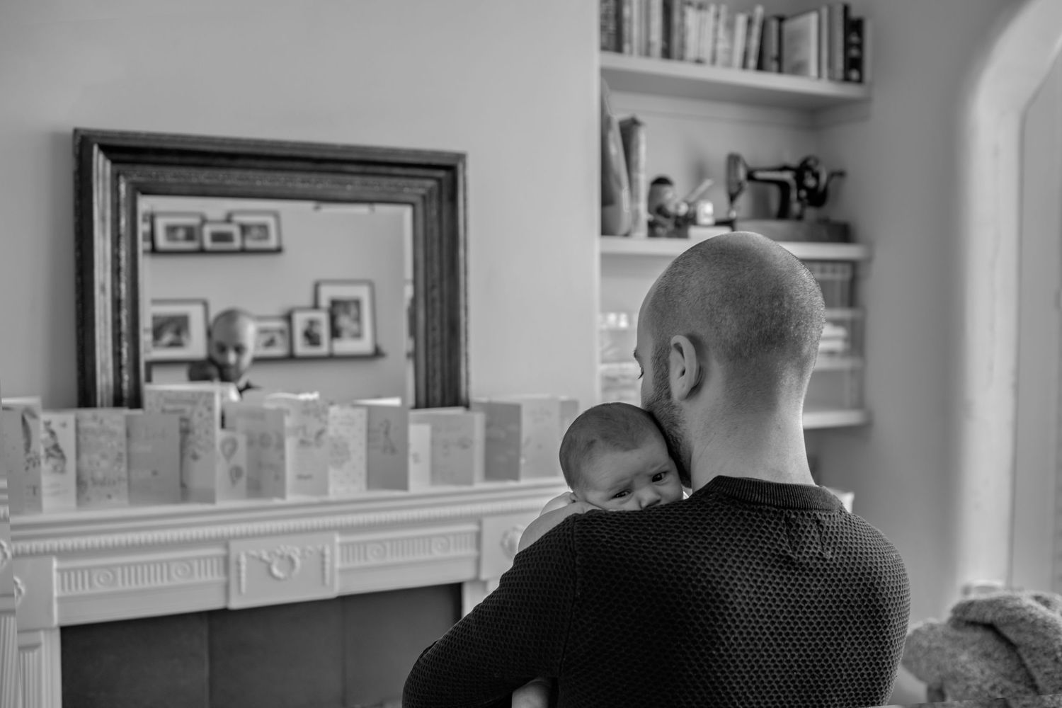 Prestwich newborn photographer capturing a tender moment between father and baby, showing their reflection in the mirror.