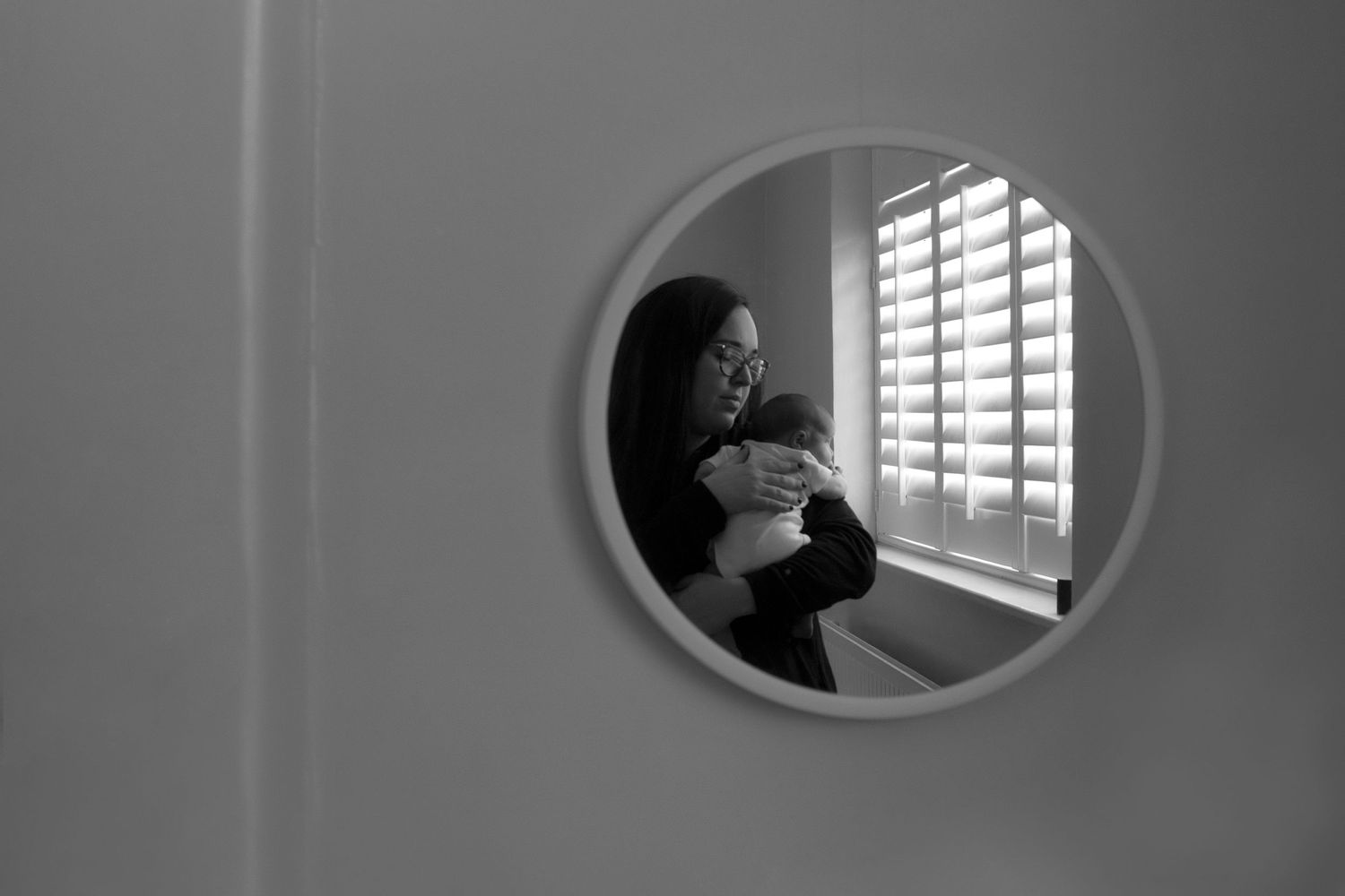 Whitefield newborn photographer captures a loving moment between mother and baby. We see their reflection in the mirror.