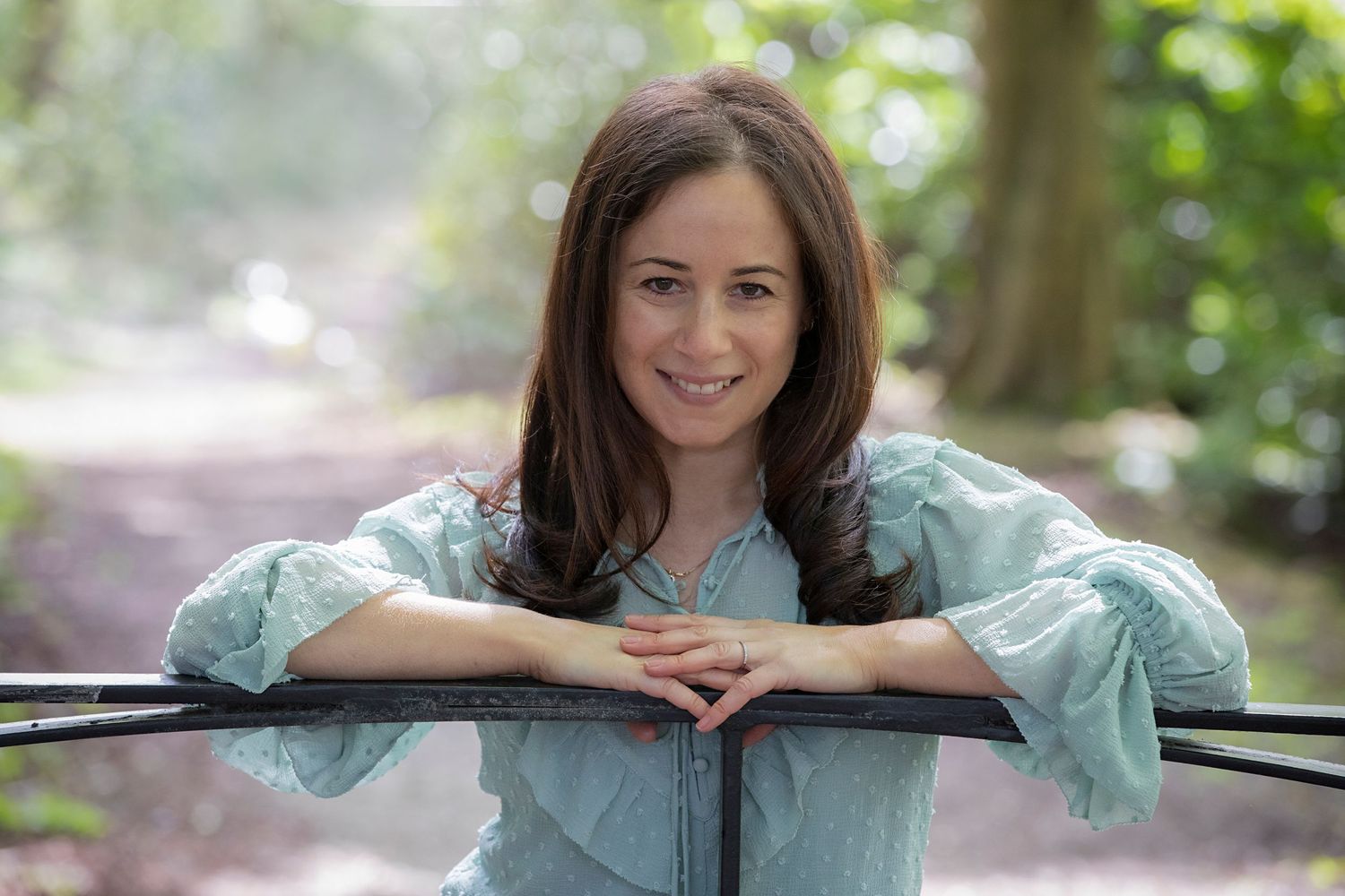 A woman leaning on a gate in a park in Whitefield, striking a relaxed and confident pose during a personal branding photo session.