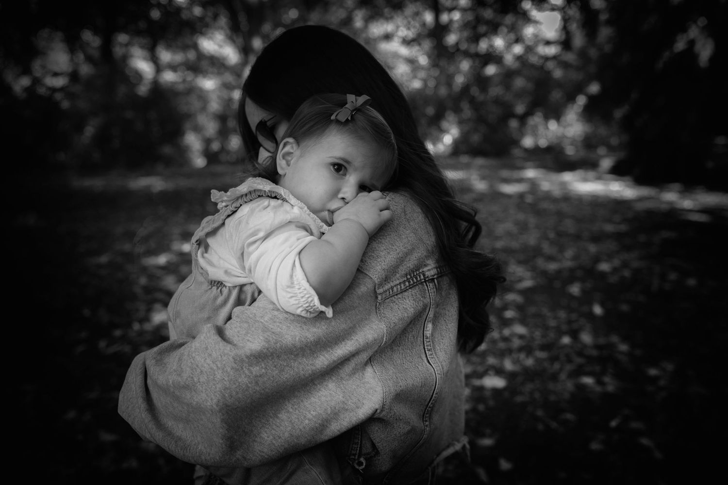 Black and white photo of a mother holding her daughter, with the daughter resting her head gently on her mother's shoulder. Whitefield