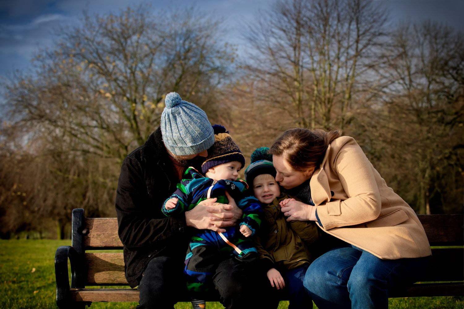Outdoor family session at a local park in Prestwich, with parents tickling their children and children laughing.