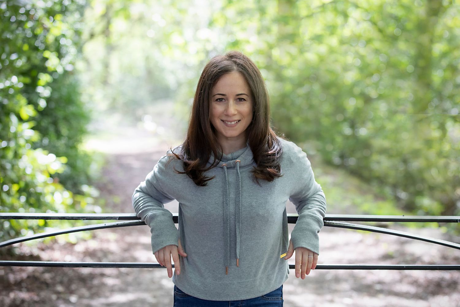 A woman leaning back against a gate in a park in Whitefield, confidently posing during a personal branding photo session.